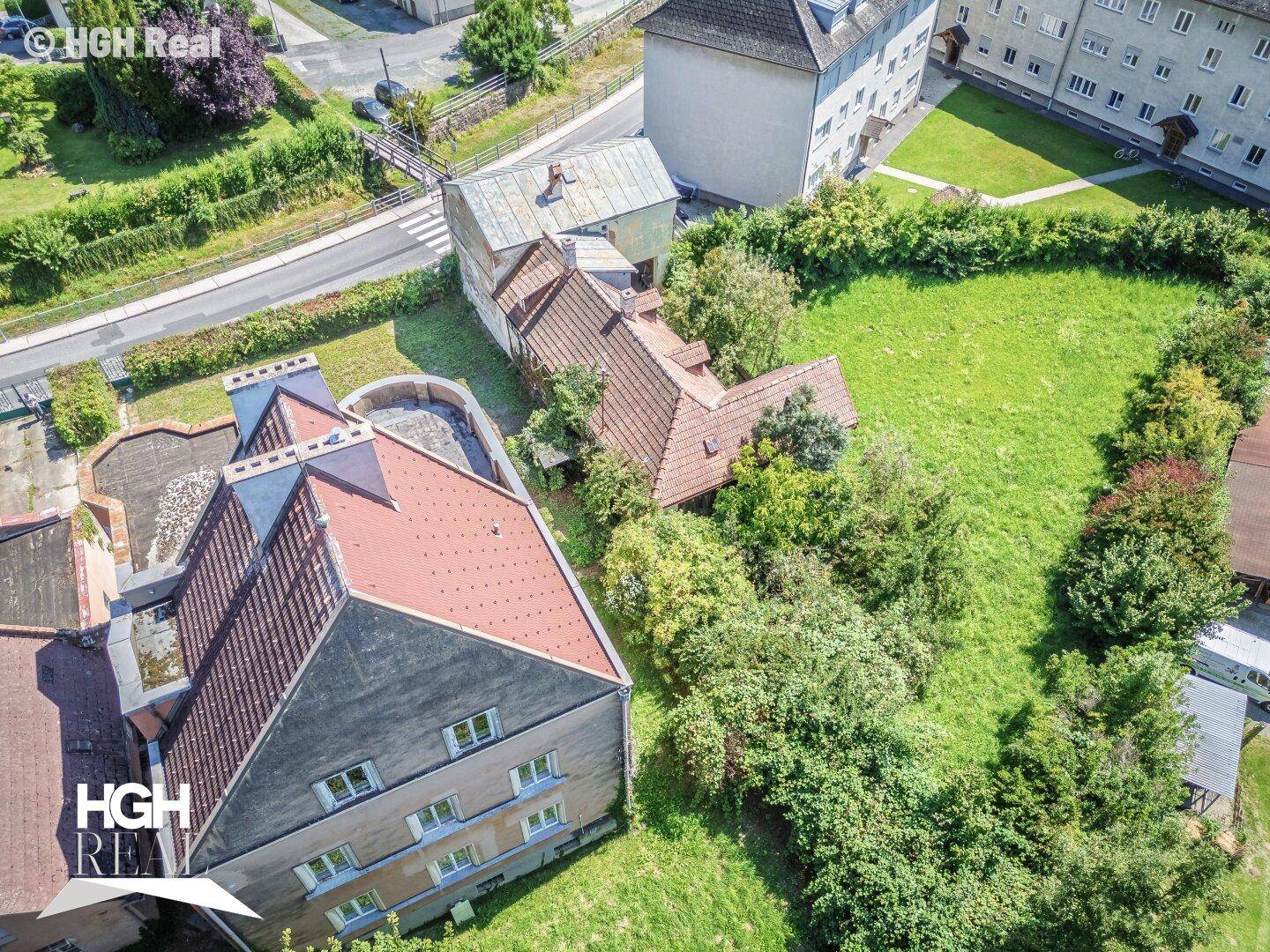 Weitläufiges Grundstück mit Altbau, viel Grünfläche und angrenzender Straße.