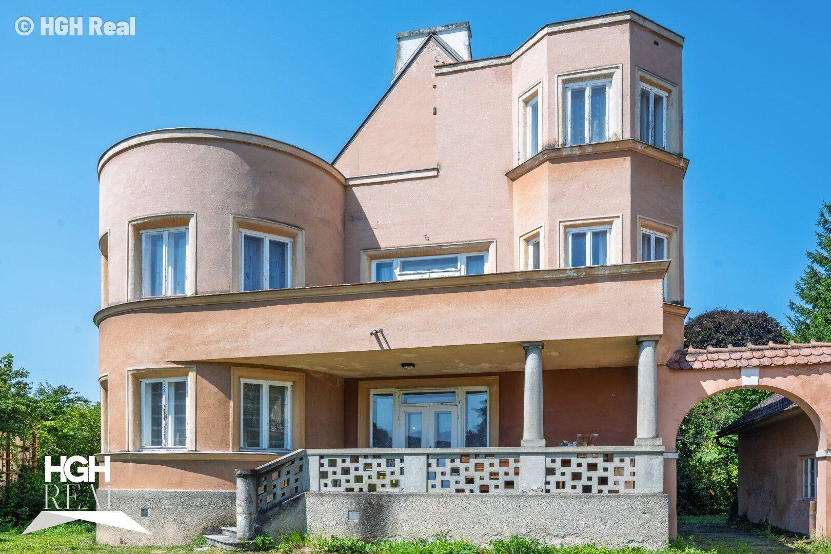 Ansicht der historischen Villa mit Säulen am Eingang und großem Grundstück.