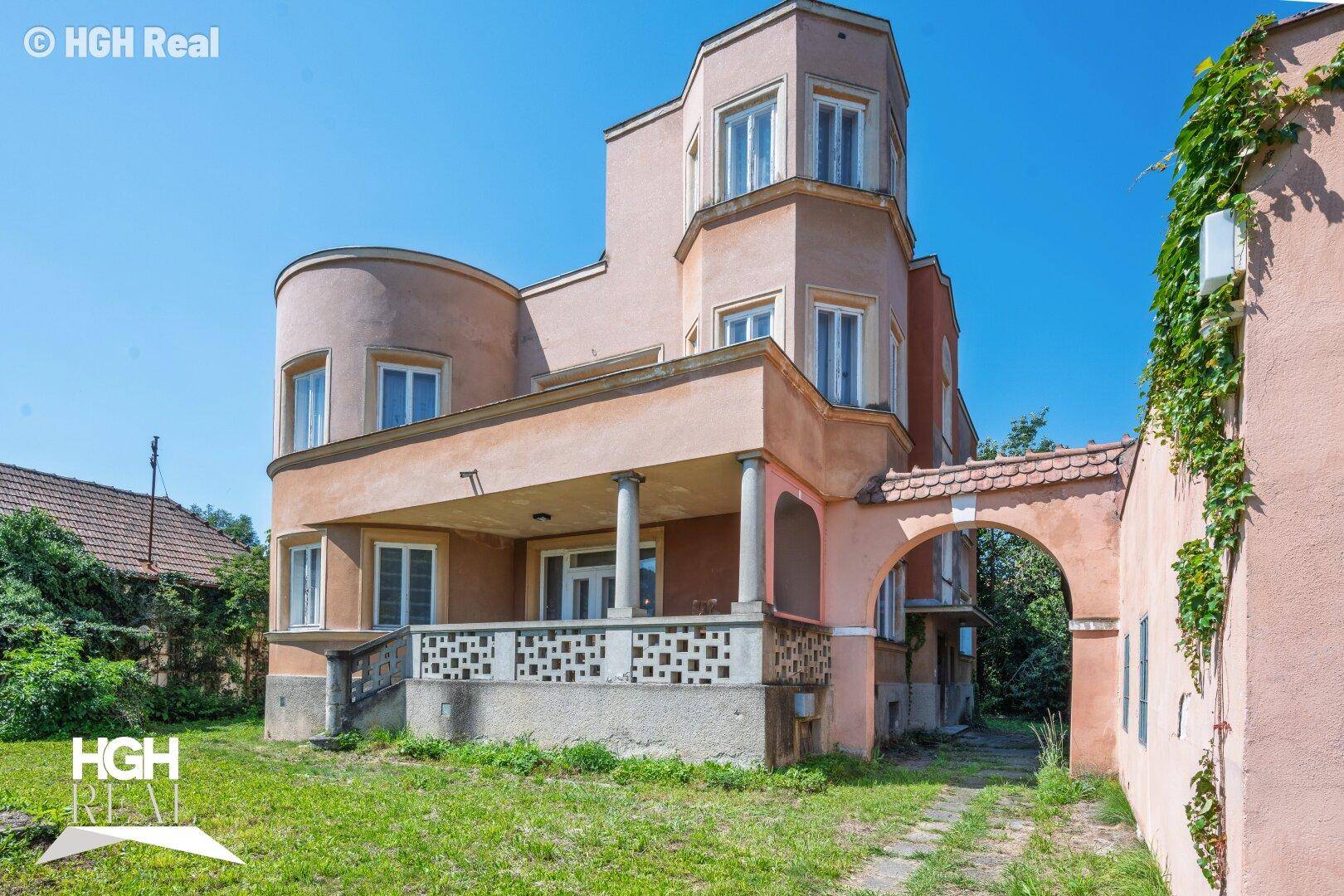 Historisches Gebäude mit markanter Architektur, Veranda und Torbogen.