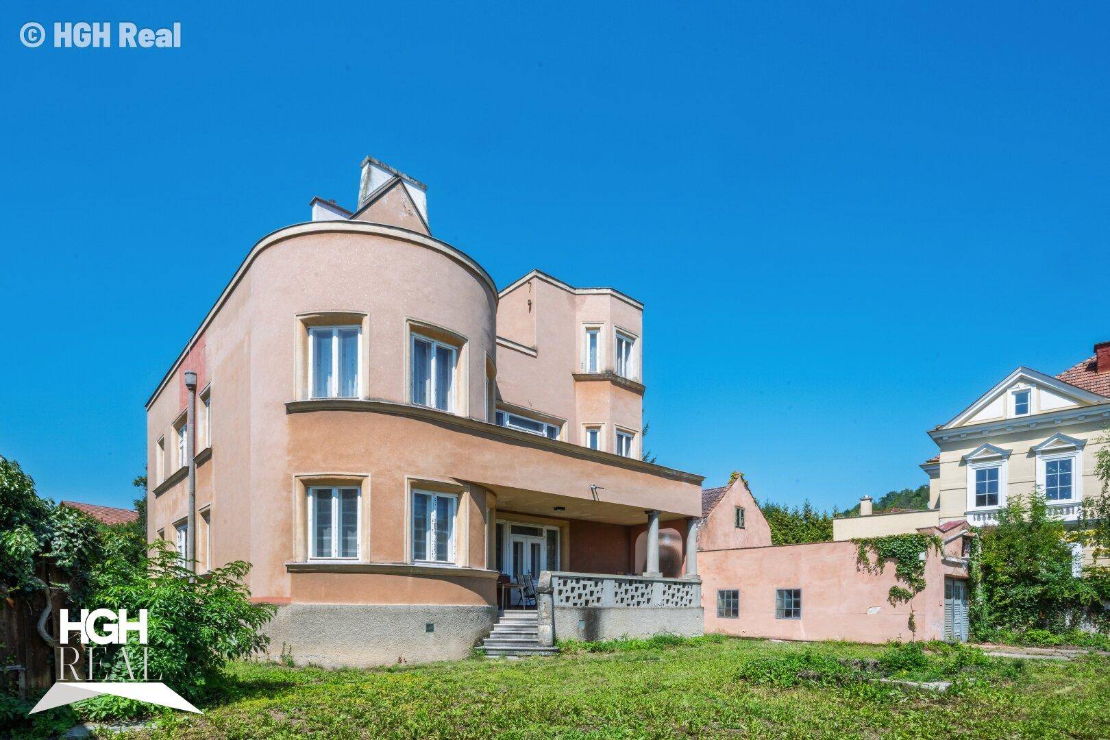 Historisches Gebäude mit markanter Architektur und einem großen Vorgarten.