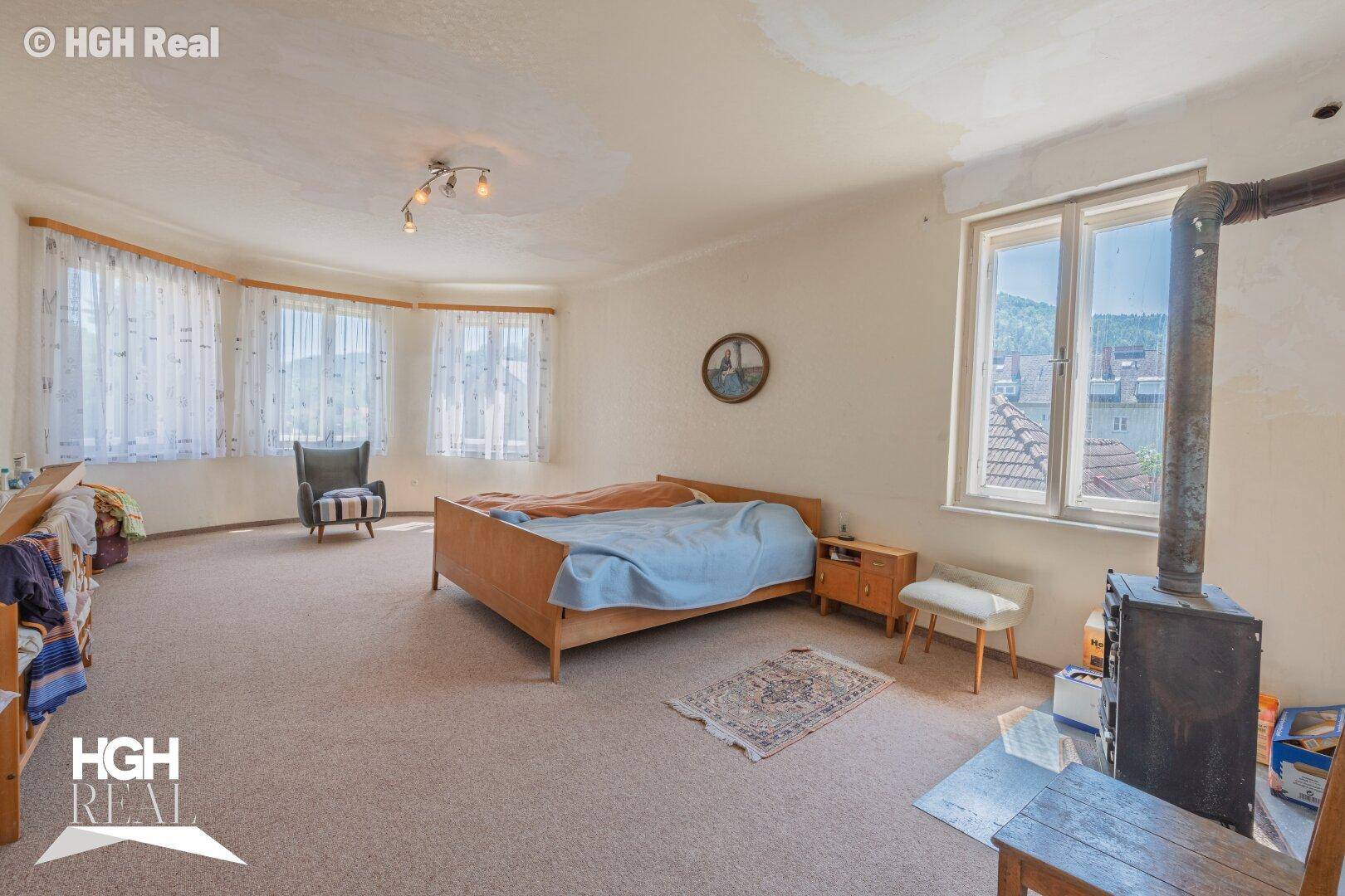 Helles Schlafzimmer mit Teppichboden, Holzofen und weitem Ausblick.