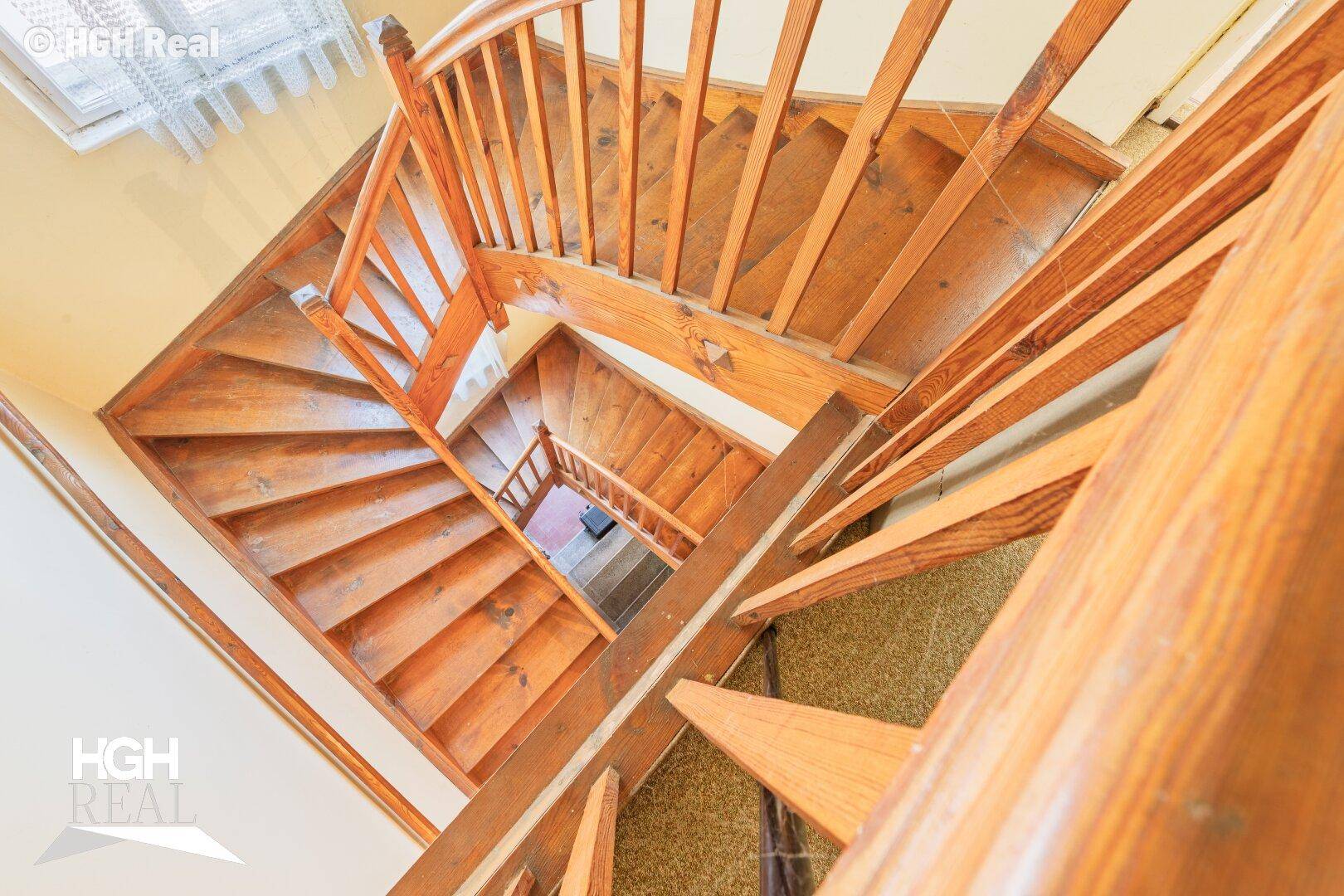 Holztreppe mit Geländer, die die verschiedenen Stockwerke des Hauses verbindet.