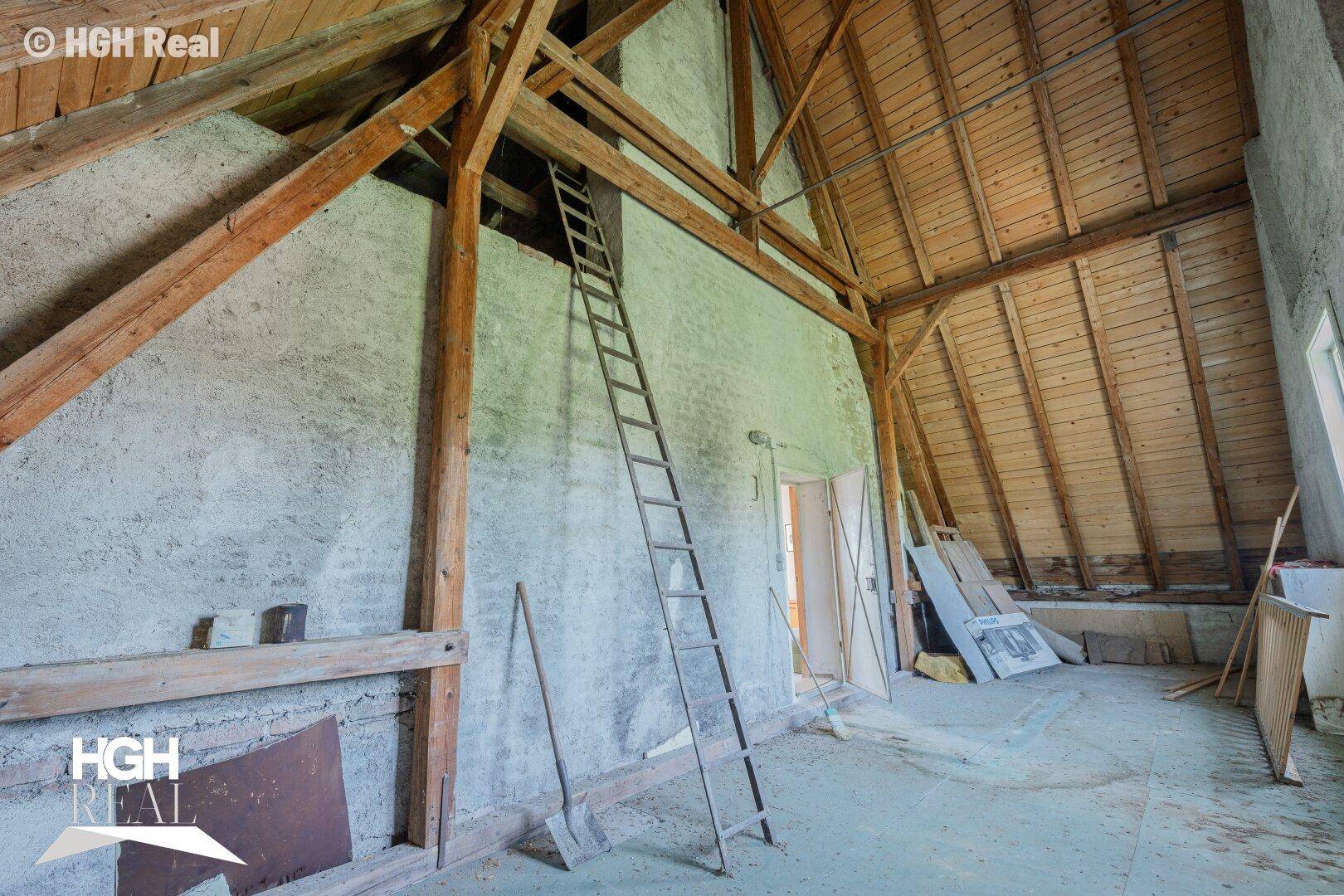 Unausgebauter Dachboden mit sichtbaren Holzbalken und einer Leiter.