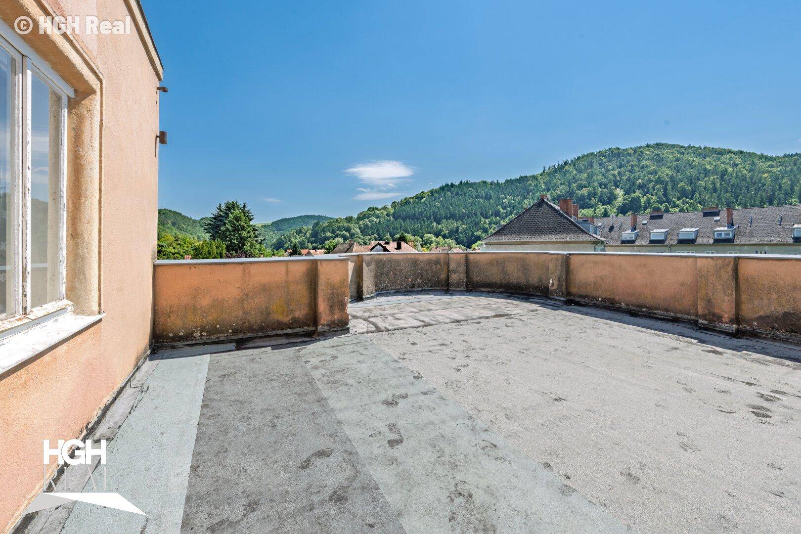Große, unmöblierte Dachterrasse mit weitem Blick über die hügelige Landschaft.