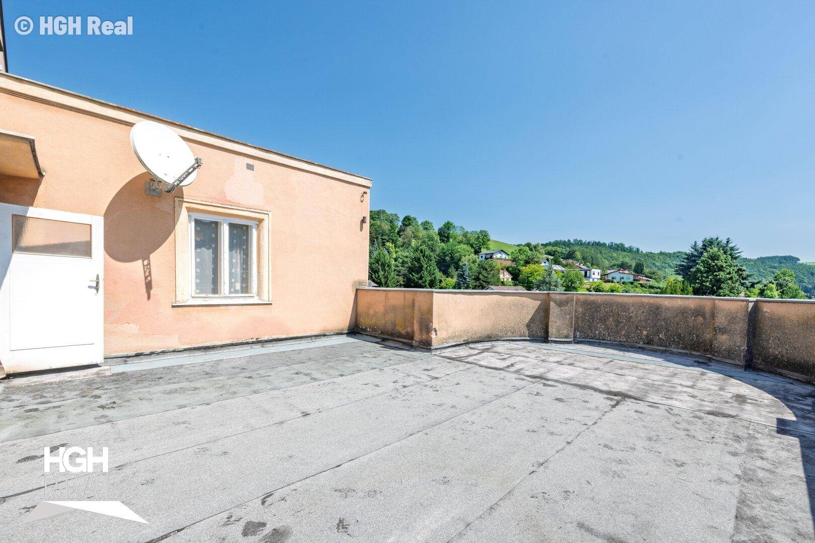 Weitläufige Dachterrasse mit Blick auf die umliegenden Hügel und Häuser.