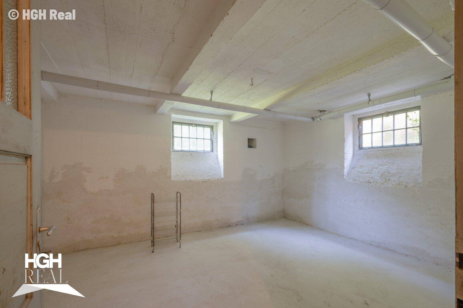 Unausgebauter Kellerraum mit kleinen Fenstern und Betonboden.