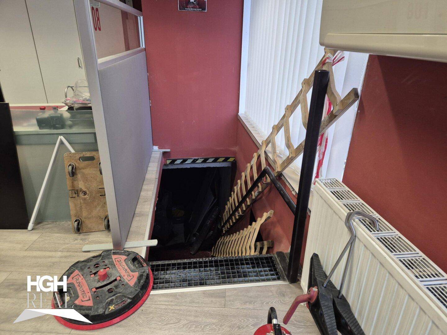 Blick von oben auf eine Treppe, die in einen unteren Bereich führt, mit Heizkörper und Fenster.