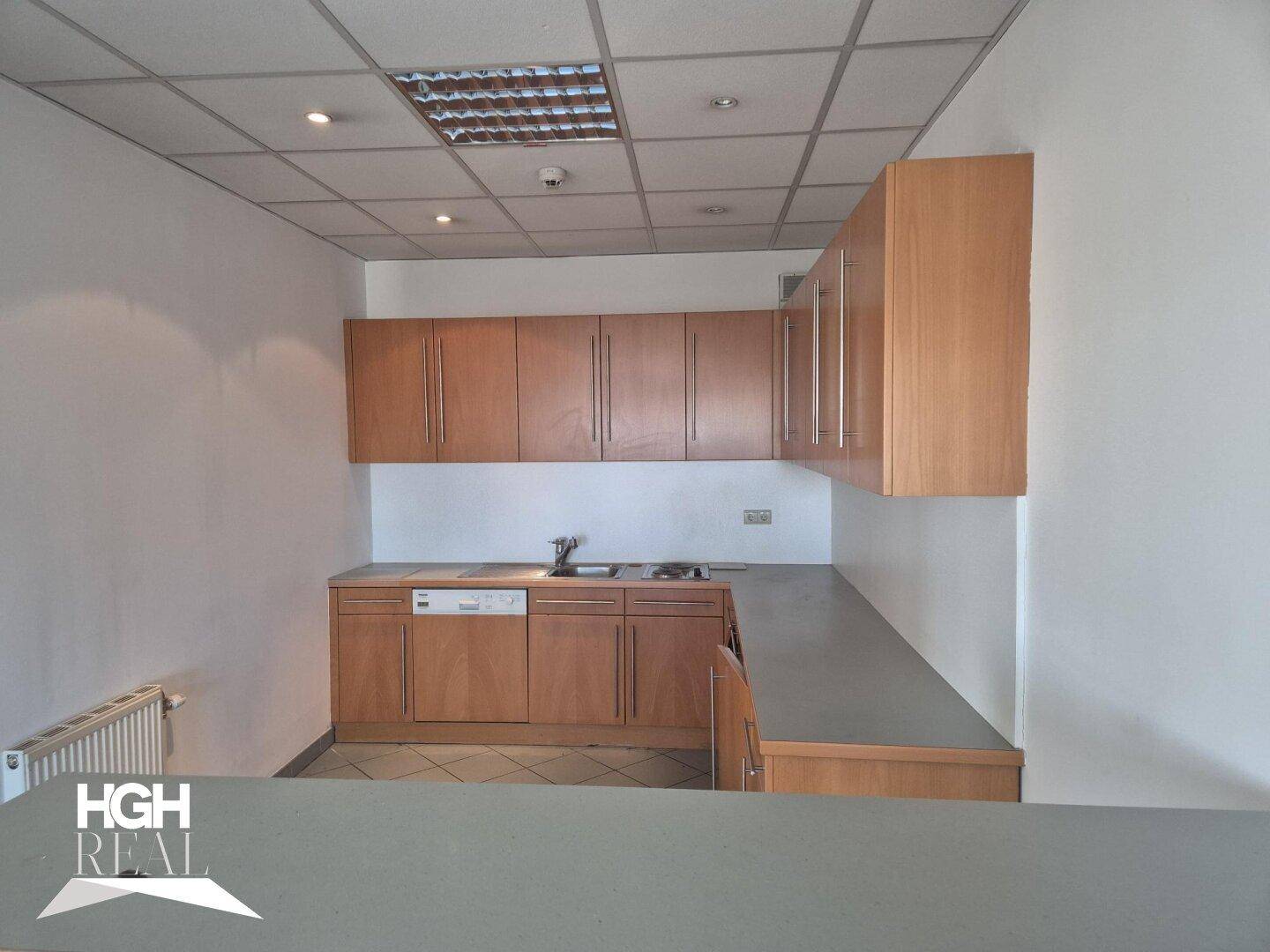 Funktionale Teeküche mit Holzschränken, Spüle und Kochfeld, ideal für Mitarbeiterpausen.
