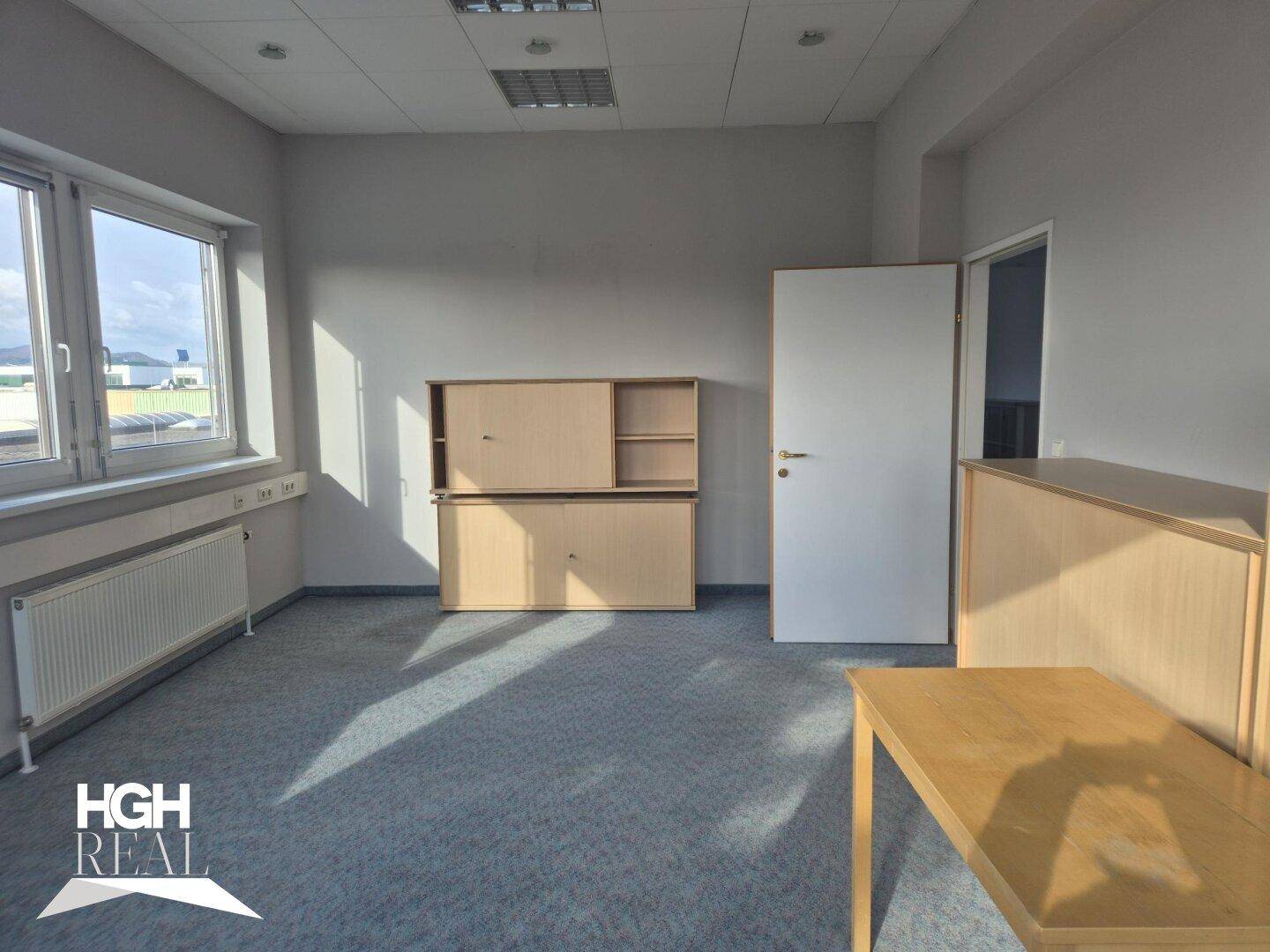 Büro mit Teppichboden, Fenstern und Holzschränken, bereit zur individuellen Einrichtung.