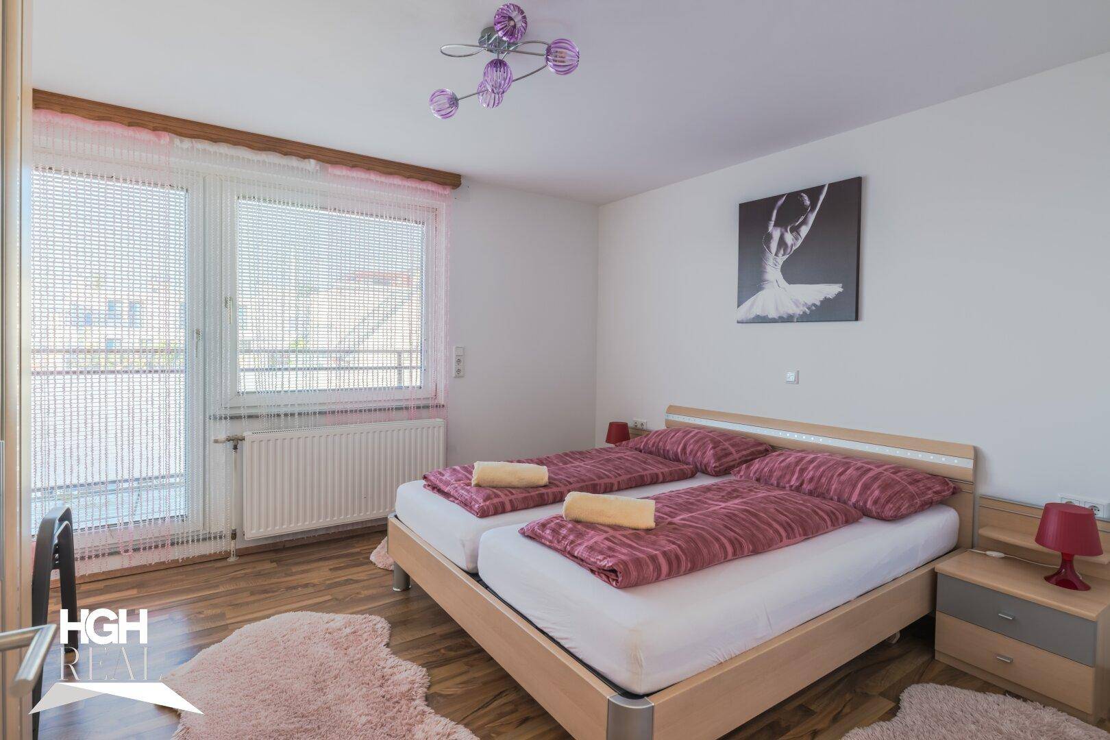 Helles Schlafzimmer mit zwei Einzelbetten, Holzboden und Zugang zum Balkon.
