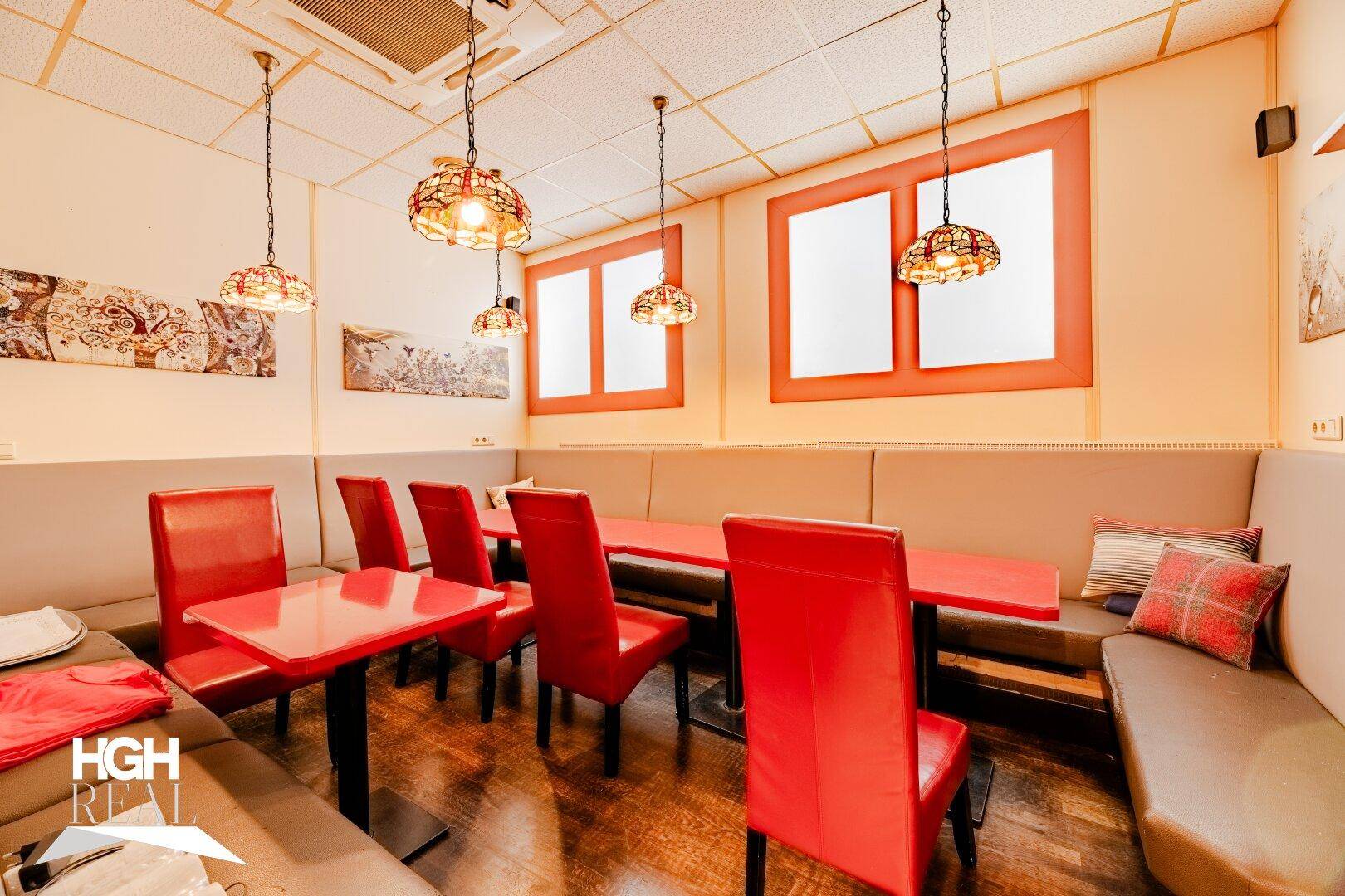 Innenbereich des Restaurants mit roten Stühlen, passenden Tischen und gemütlichen Sitzbänken entlang der Wände für Gäste.
