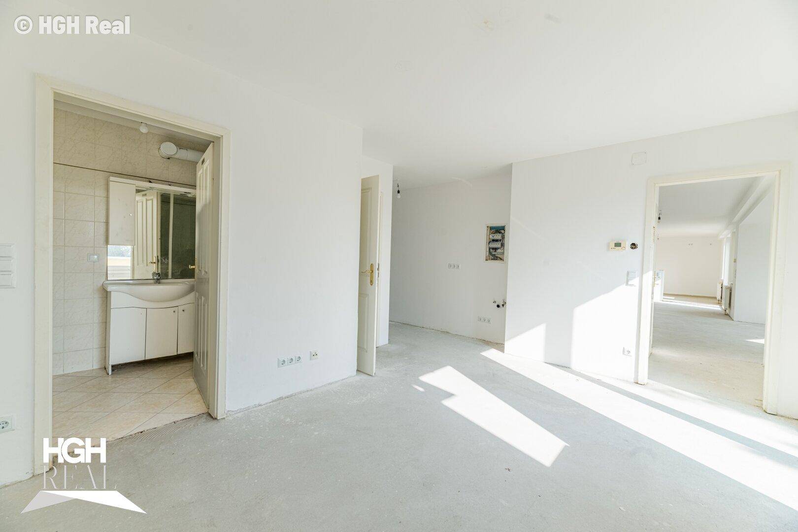 Heller Innenraum mit mehreren Türen und Blick in ein Badezimmer.