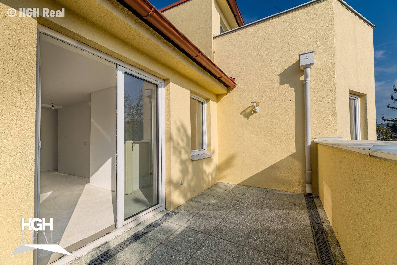 Sonniger Terrassenbereich mit Fliesenboden und Blick auf die Umgebung.