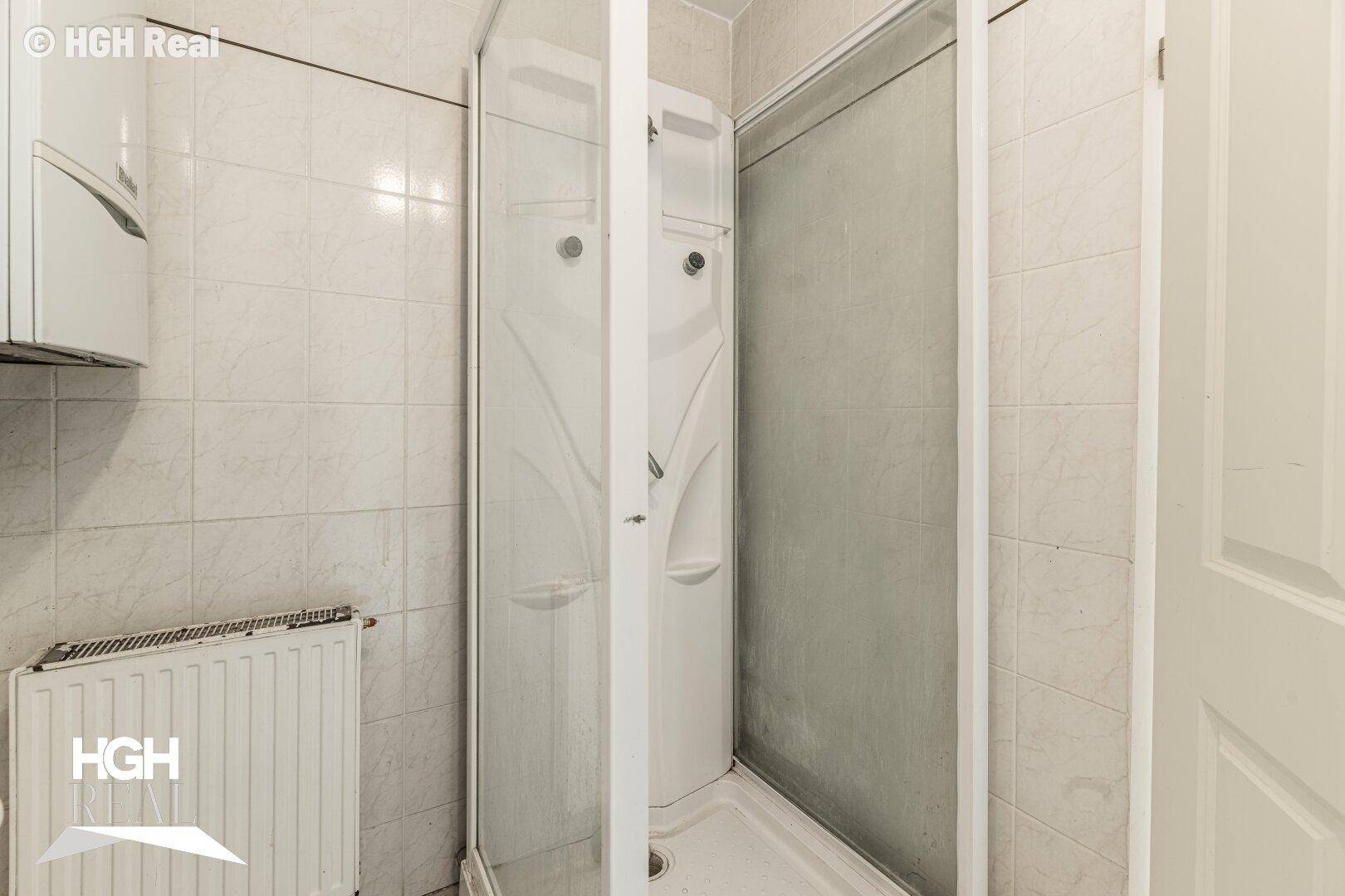 Kleines Badezimmer mit Duschkabine und weißen Fliesen an den Wänden.