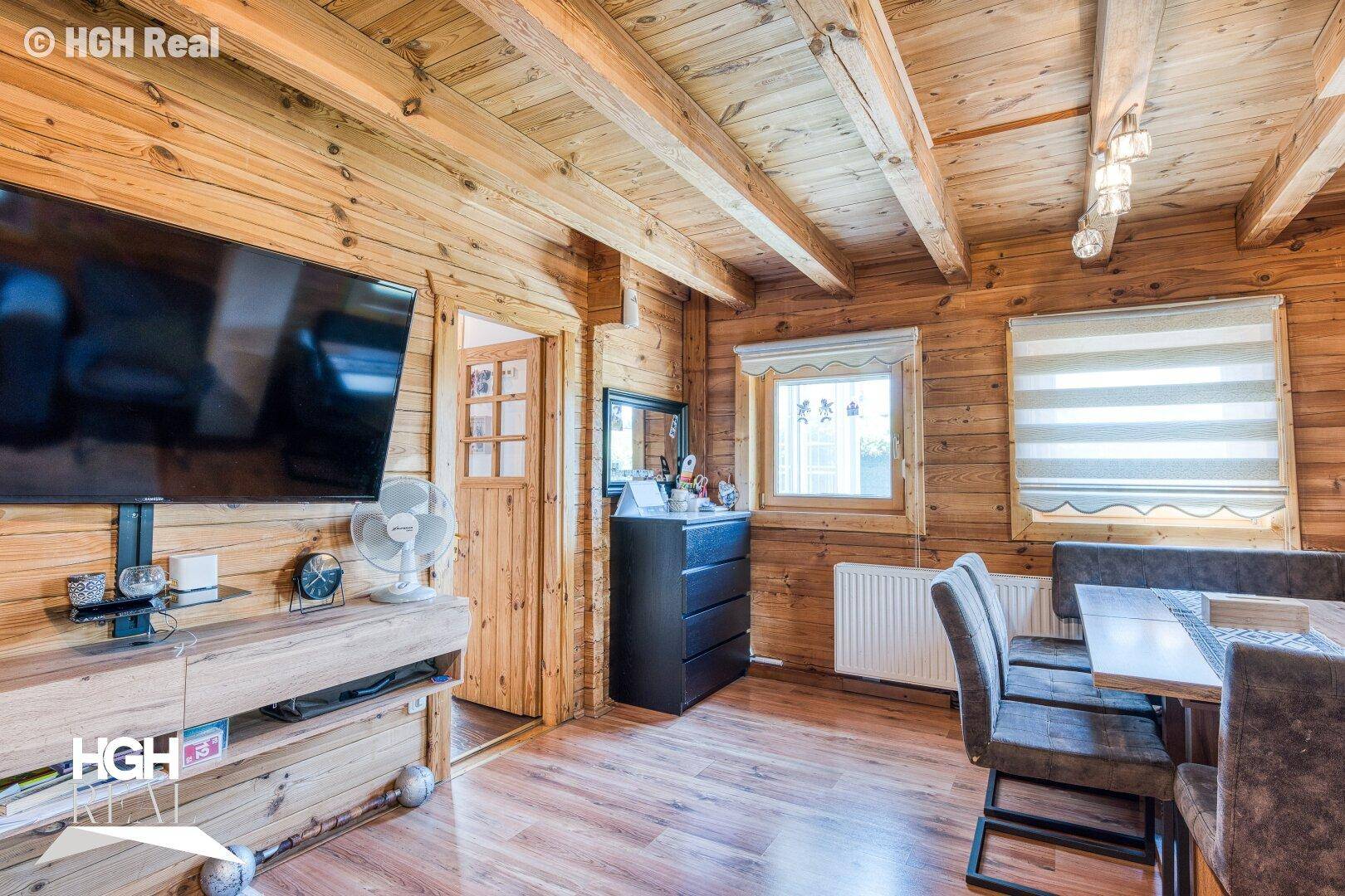 Gemütlicher Wohn-Essbereich mit Holzwänden, Holzbalkendecke und einem Essbereich.
