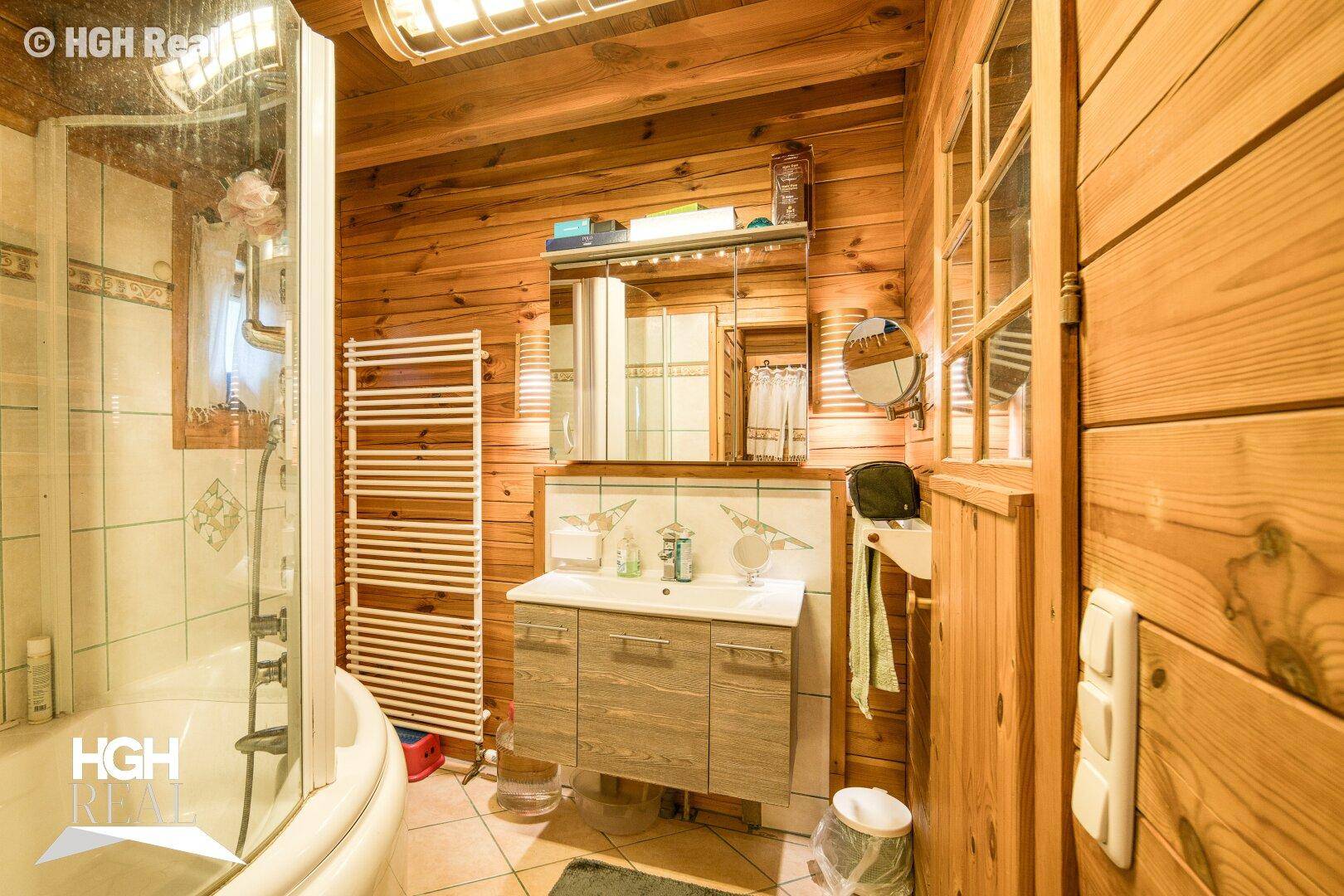 Badezimmer mit Holzwänden, Duschkabine, Einzelwaschbecken und beheiztem Handtuchhalter.