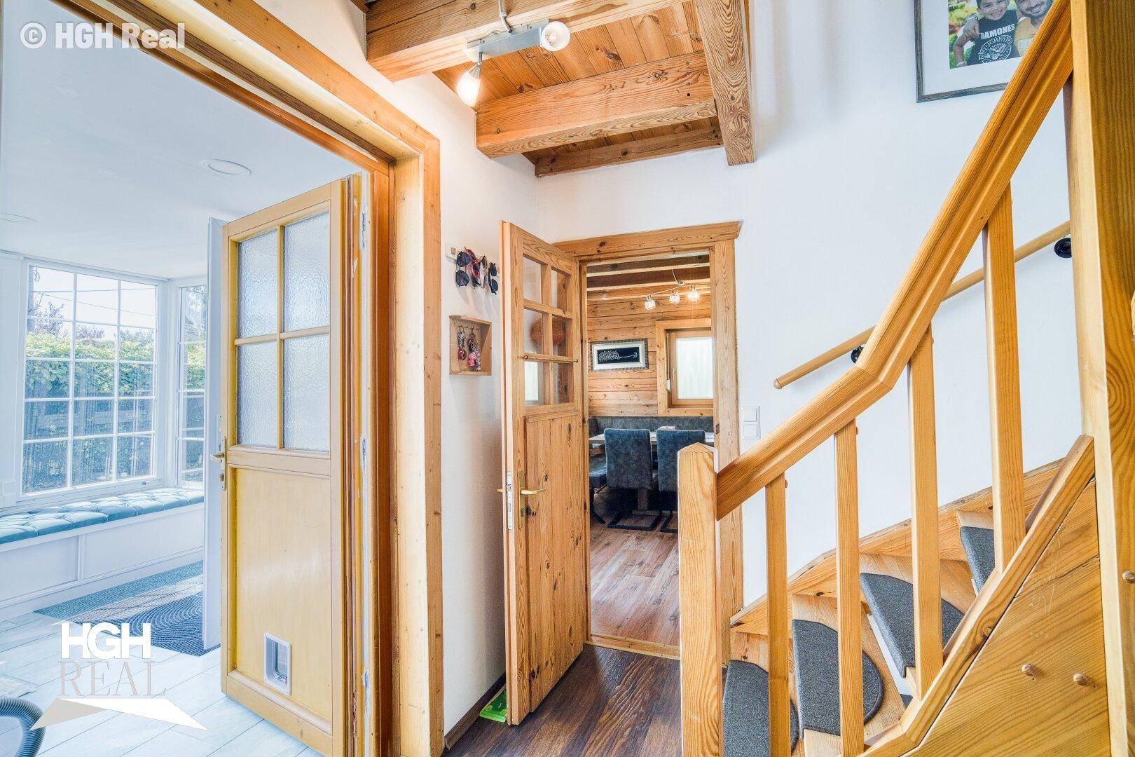 Gemütlicher Flur mit Holztreppe, Holztüren und sichtbaren Deckenbalken, die zu den Wohnbereichen führen.