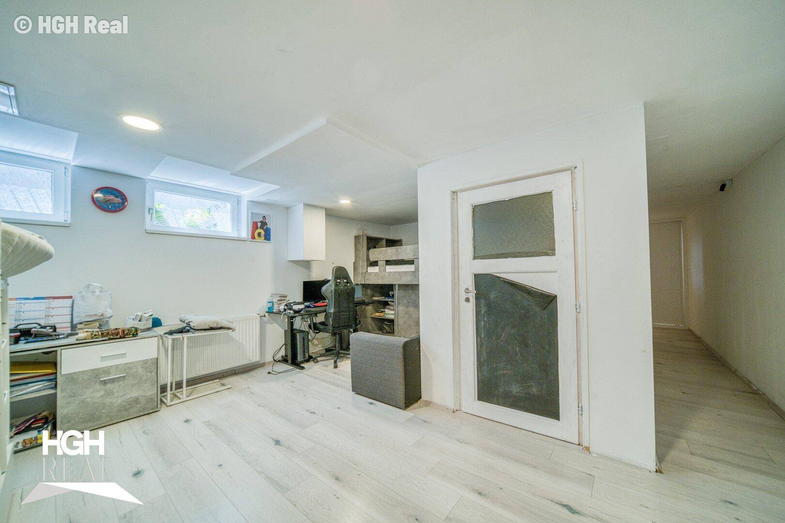 Vielseitig nutzbarer Kellerraum mit kleinen Fenstern und hellem Boden, ideal als Hobby- oder Gästezimmer.