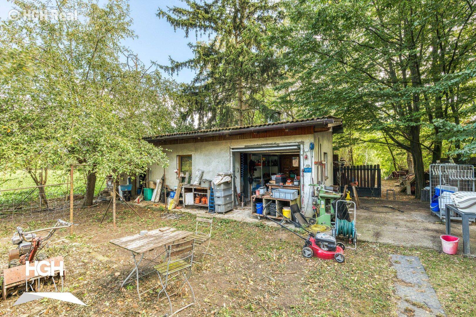 Gartenbereich mit einem Schuppen, Werkzeugen und einem kleinen Sitzbereich.
