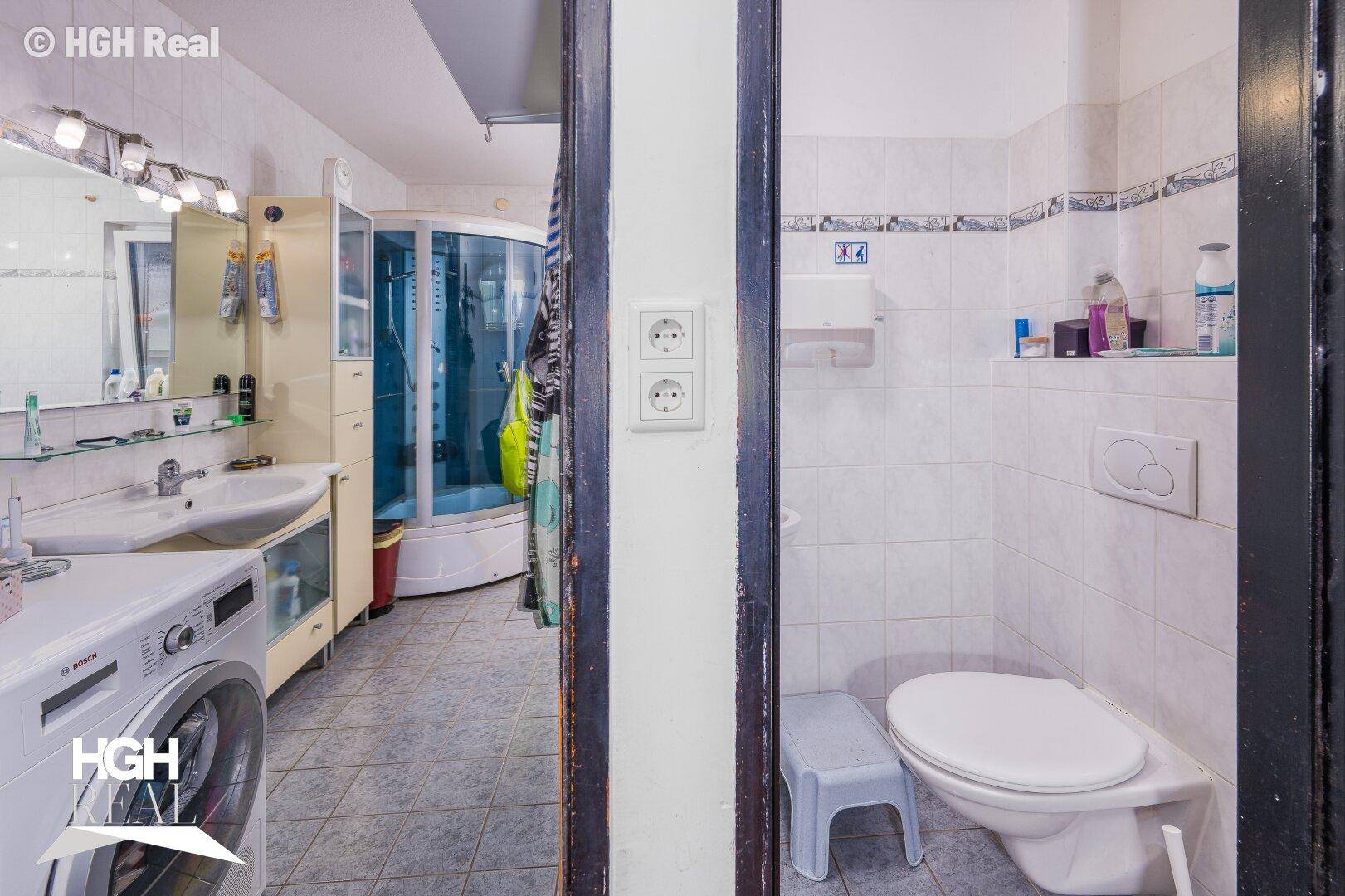 Separate Toilette neben dem Badezimmer mit weißen Fliesen.