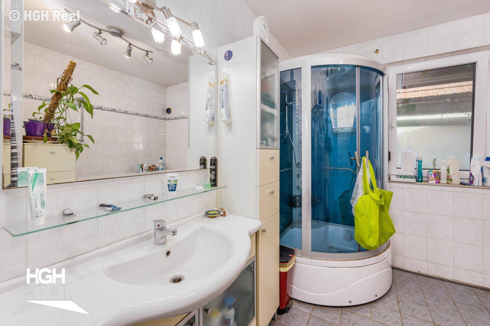 Badezimmer mit Duschkabine, Einzelwaschbecken und hellen Fliesen.