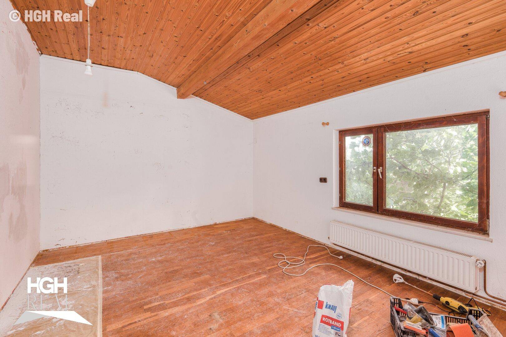 Schlafzimmer in Renovierung mit Holzdecke, Holzboden und großem Fenster.