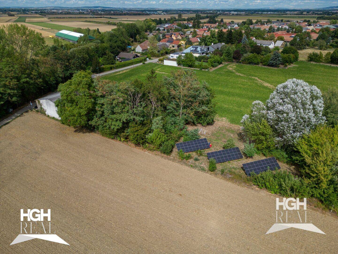 Luftaufnahme eines Grundstücks mit Solaranlagen, umgeben von Feldern und einem Wohngebiet.