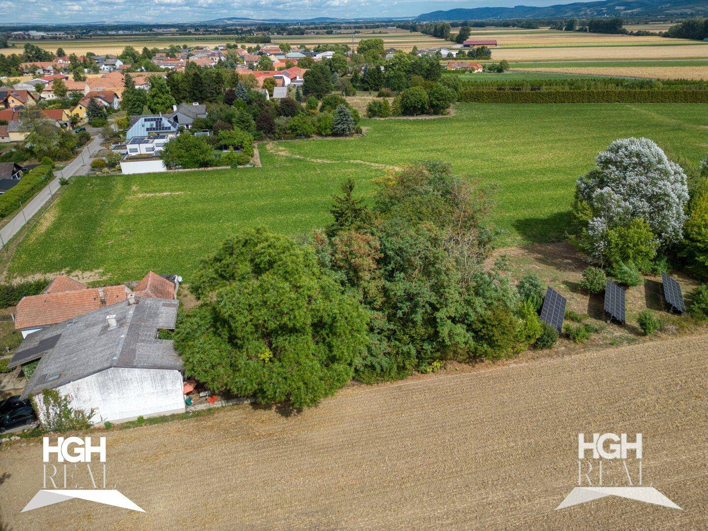 Luftaufnahme eines Anwesens mit Haus, Bäumen, Solaranlagen und weiten Feldern im Hintergrund.