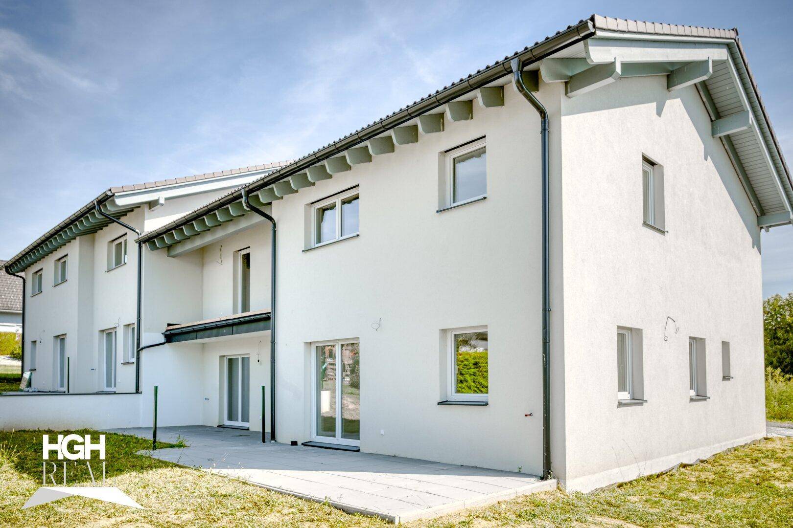 Ansicht der Rückseite eines modernen Reihenhauses mit kleiner Terrasse und Gartenbereich.