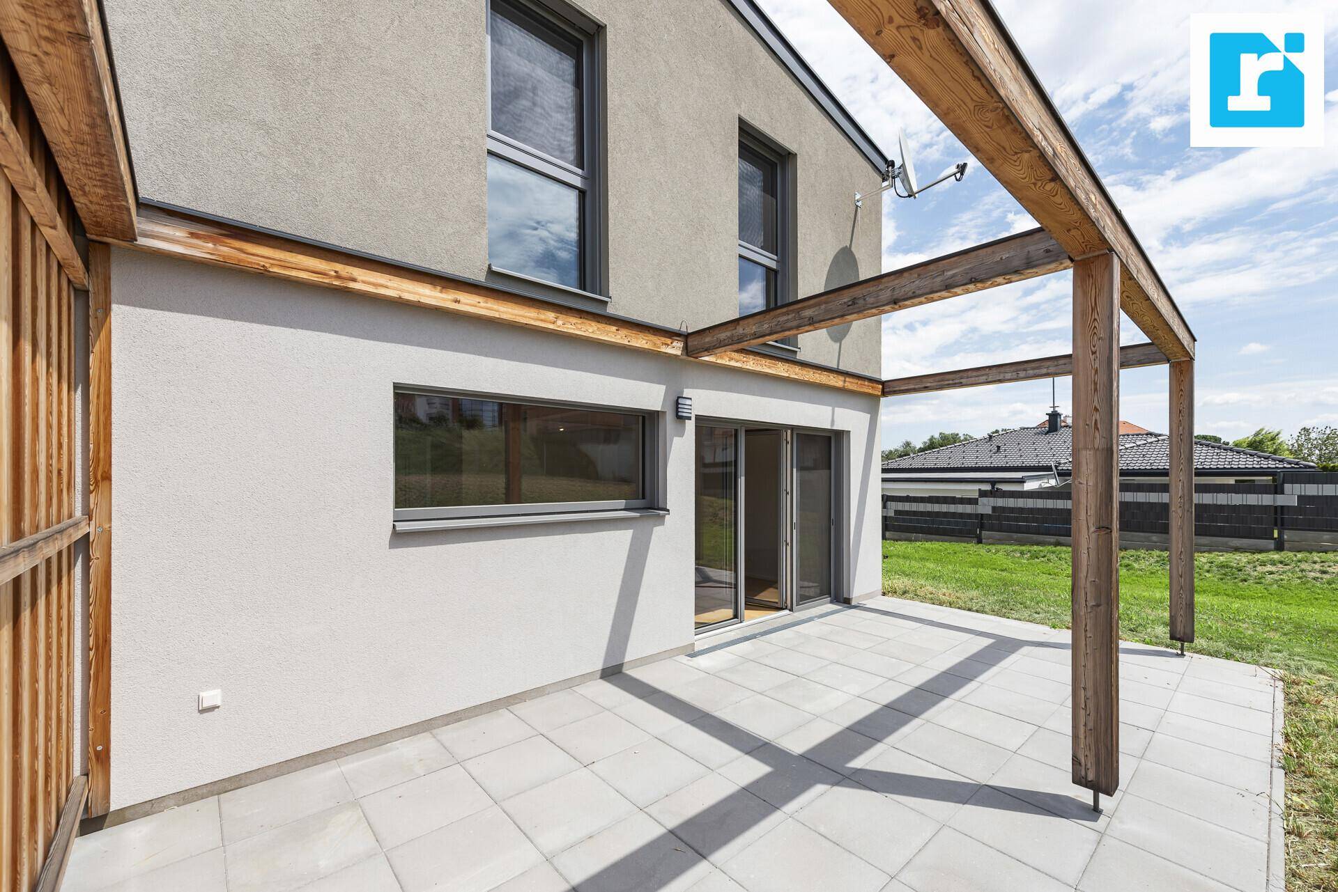 Terrasse mit Holzpergola und Blick auf den Garten und die Umgebung.