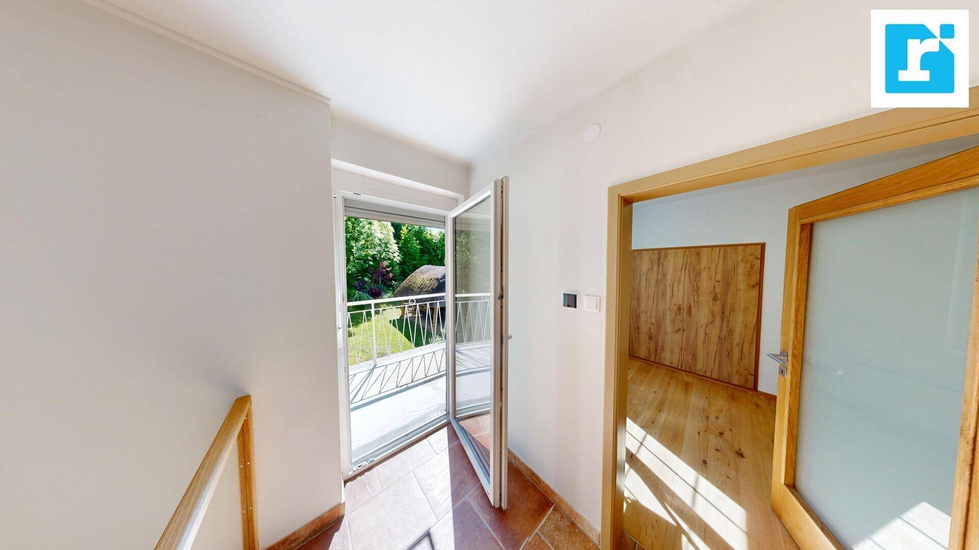 Heller Flur mit Zugang zum Balkon und Holztüren, gefliester Boden.
