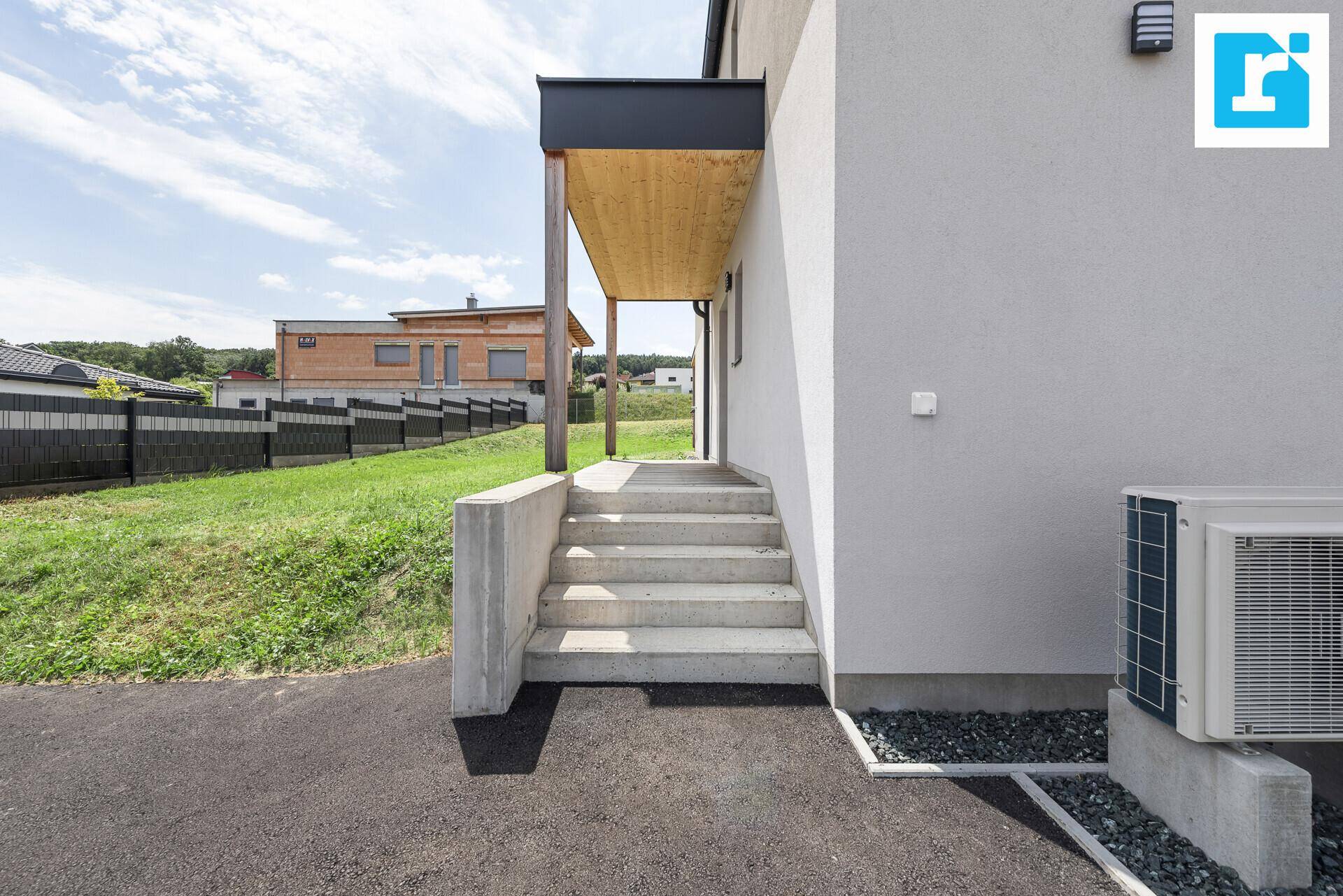 Seitlicher Zugang zum Haus mit Betontreppe und installierter Klimaanlage.