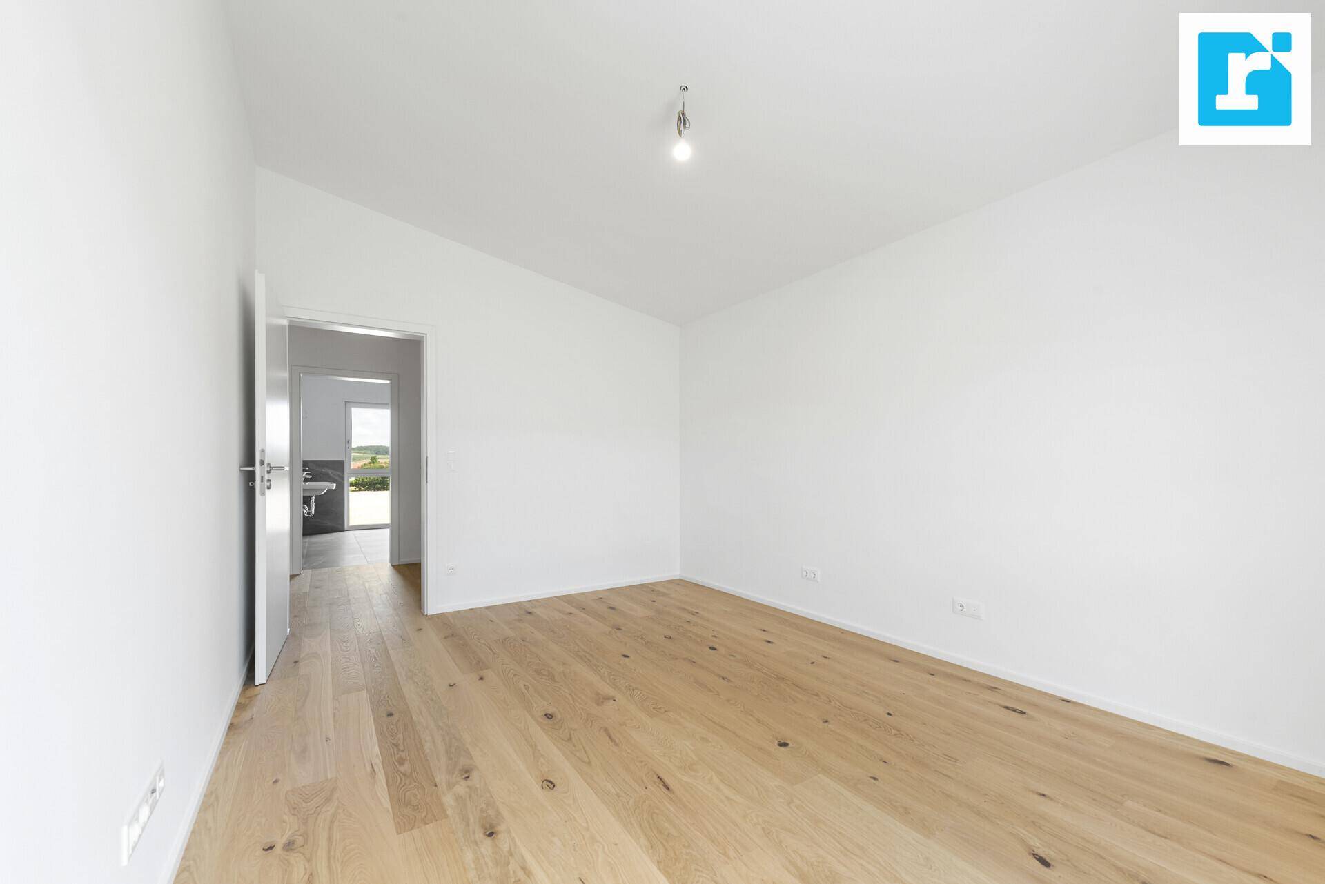Geräumiges Zimmer mit Holzboden und Zugang zu einem modernen Badezimmer.