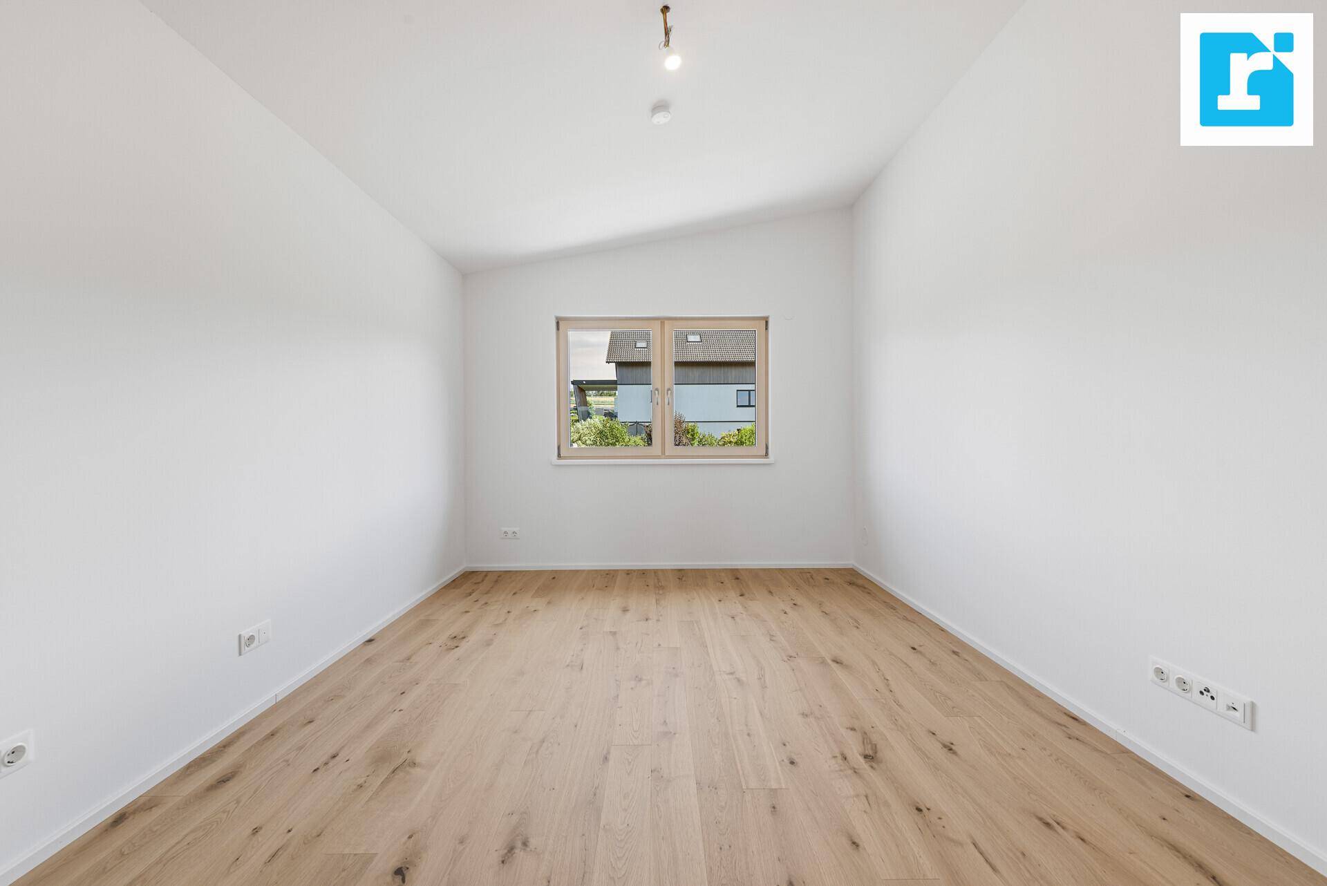 Helles Schlafzimmer mit Parkettboden, Dachschräge und Fenster für natürliches Licht.