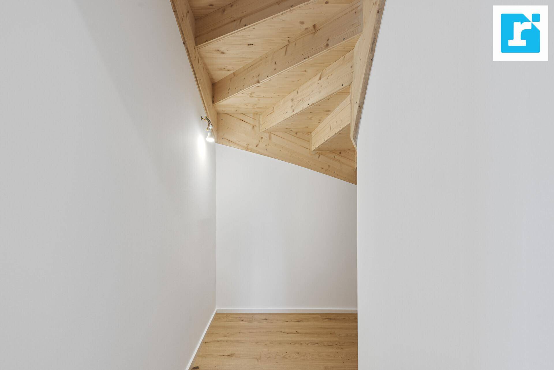 Blick auf die Holztreppe mit natürlicher Beleuchtung und Holzbalkendecke.