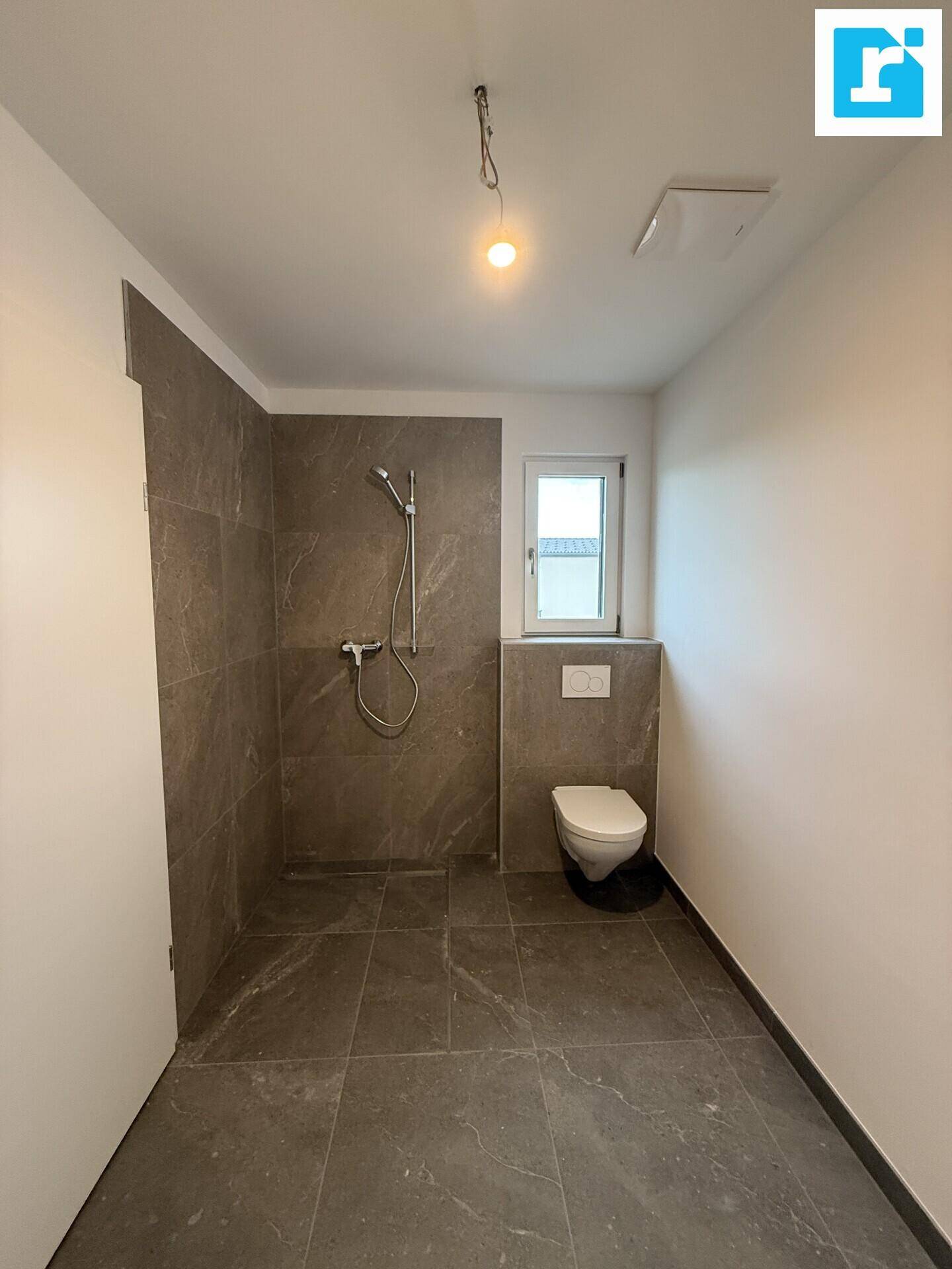 Modernes Badezimmer mit Dusche, WC und Fenster für Tageslicht.