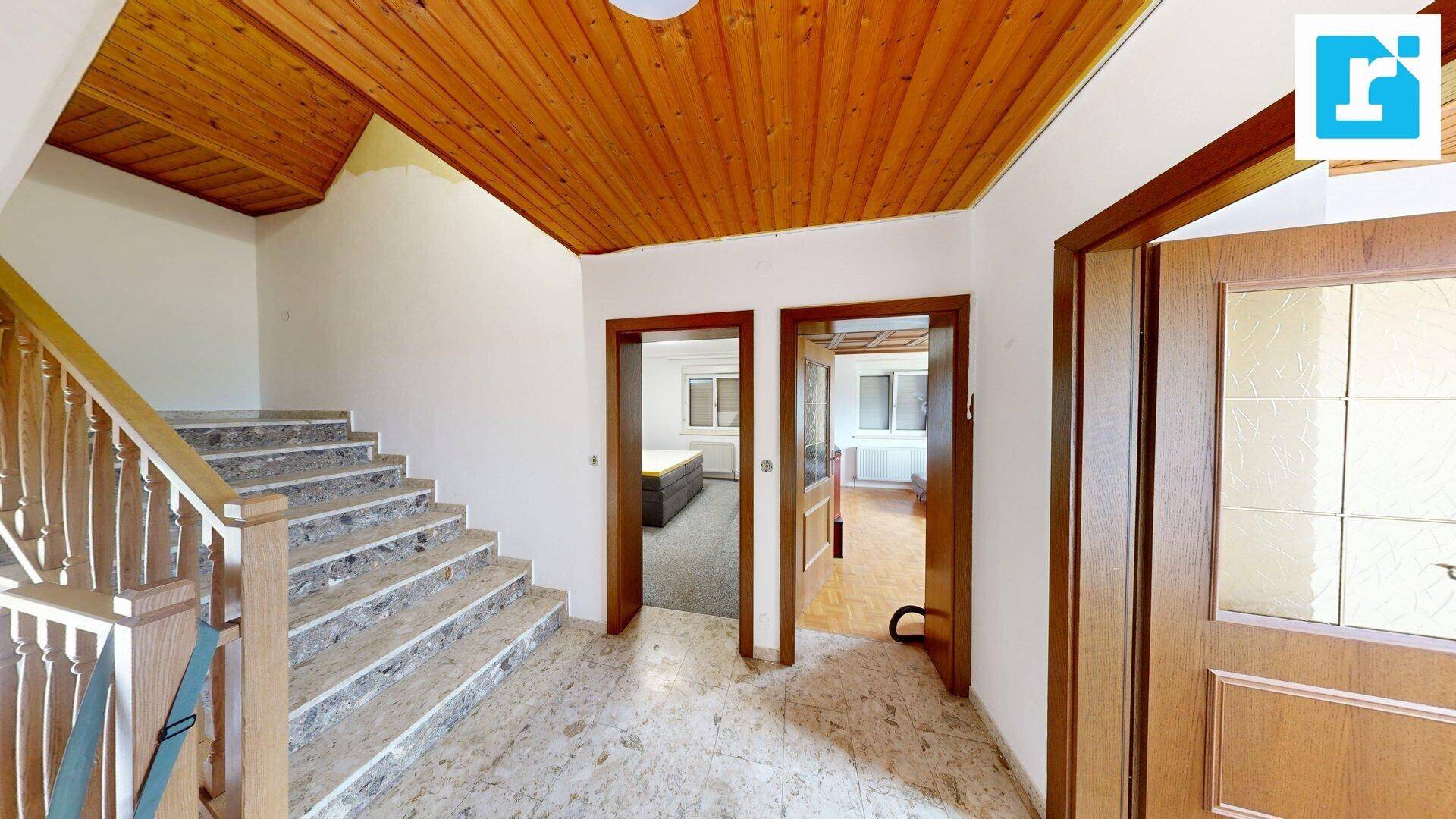 Heller Flur mit Marmorboden und Holzdecke, bietet Zugang zu mehreren Zimmern.