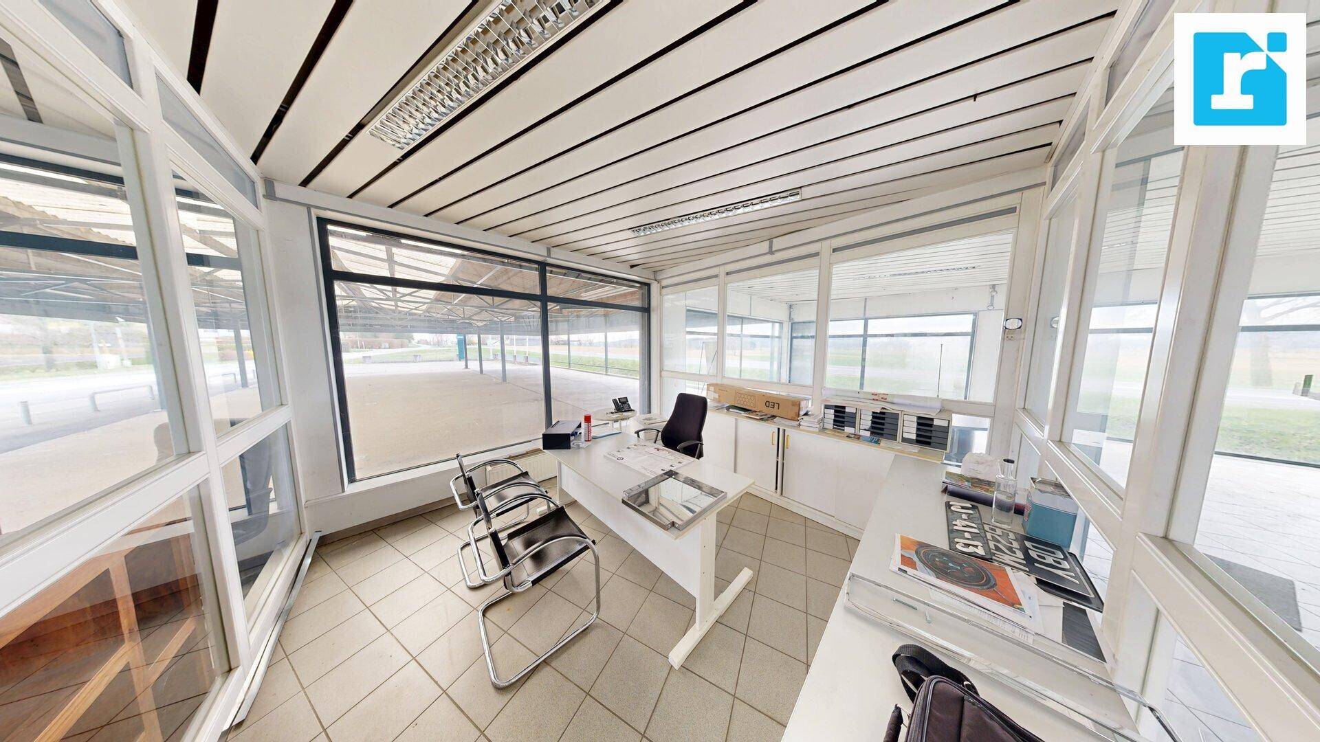 Helles Büro mit großen Fenstern, Fliesenboden und moderner Einrichtung, ideal für Beratungsgespräche.