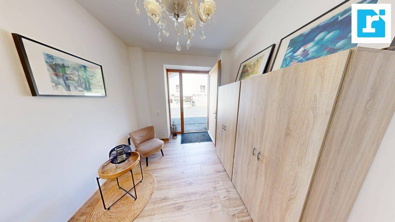 Heller Eingangsbereich mit Holzoptikboden, Einbauschränken und einem eleganten Kronleuchter an der Decke.