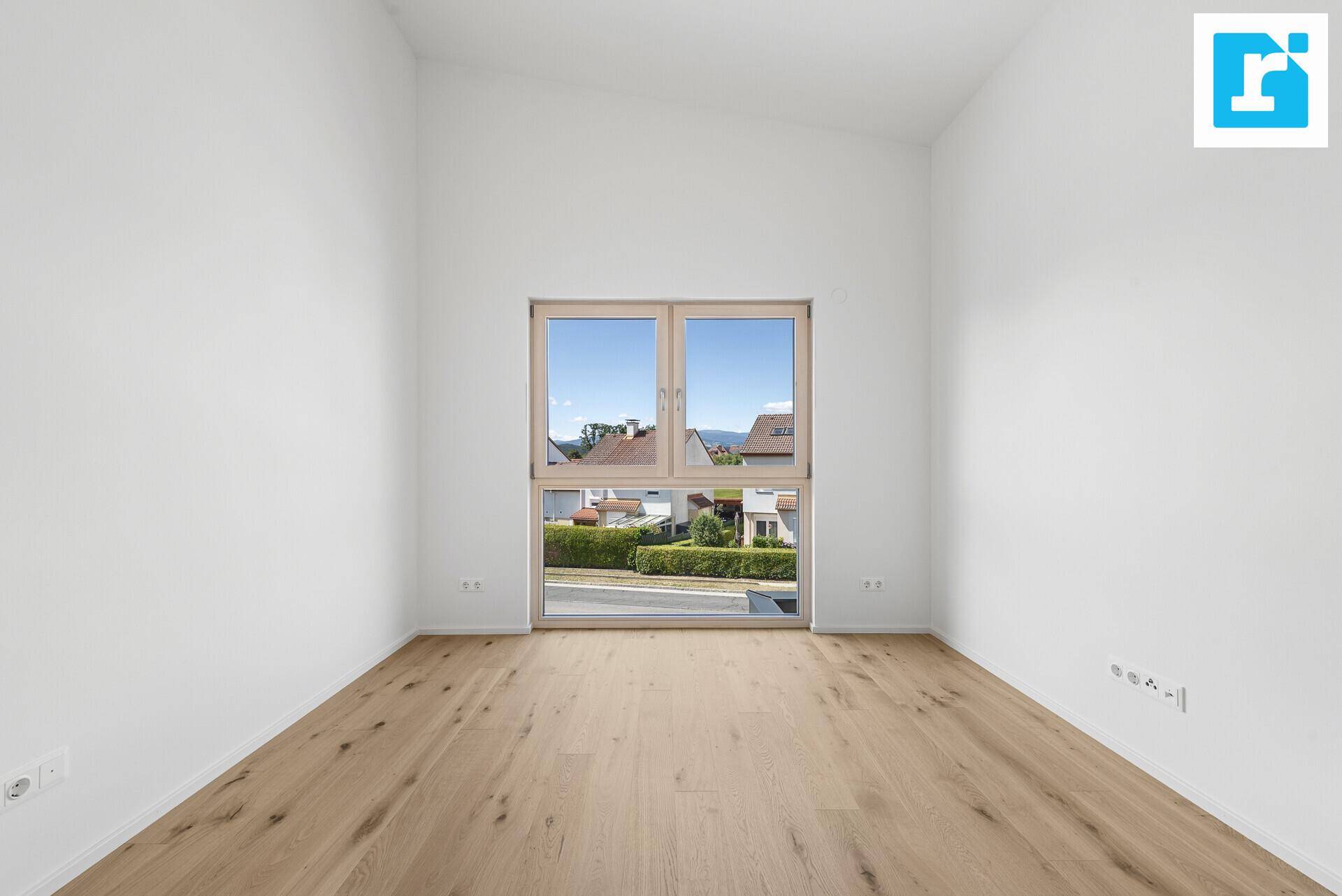 Geräumiges Zimmer mit Parkettboden und großem Fenster mit Blick auf die Umgebung.