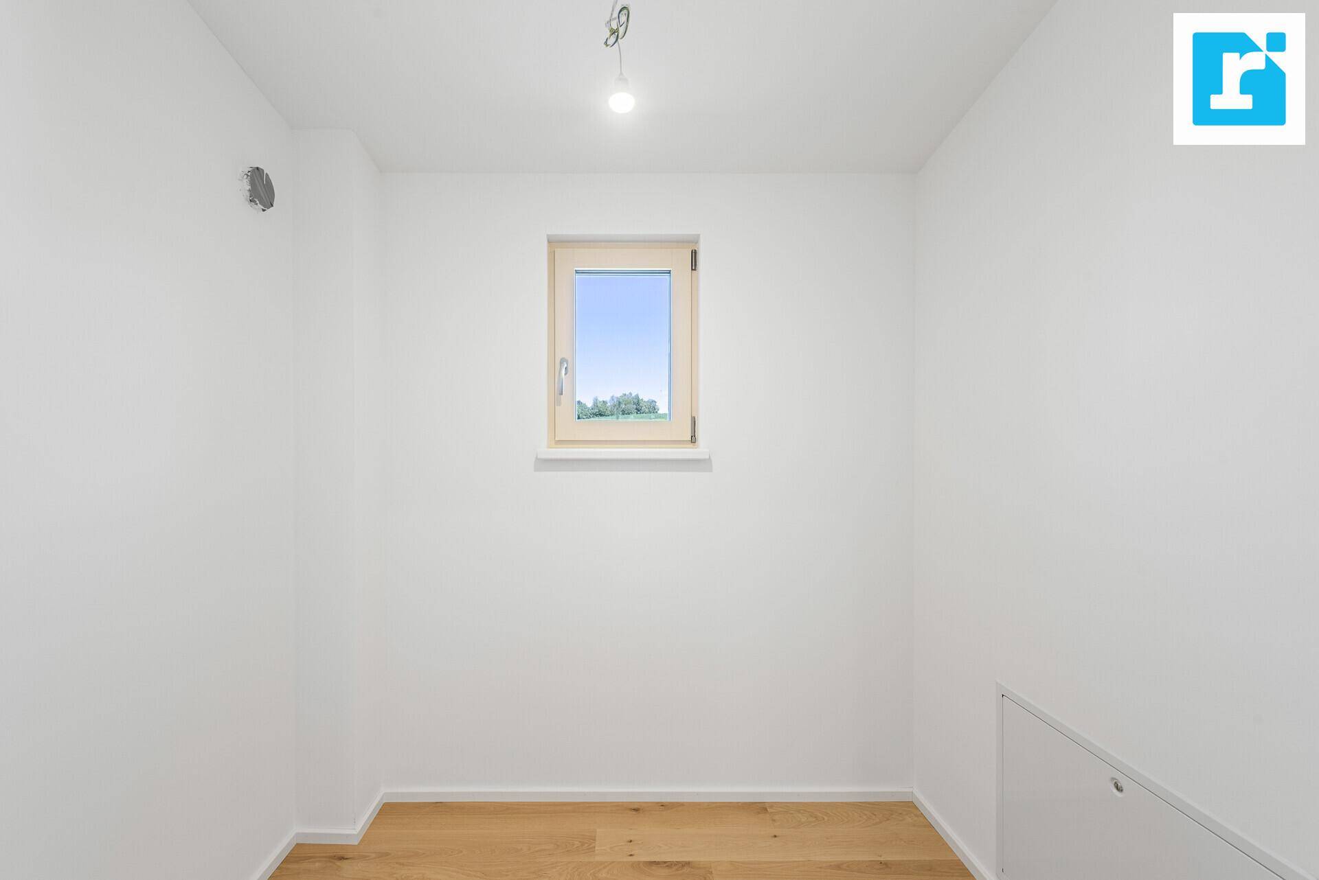 Kleiner, heller Raum mit Holzfußboden und Fenster, ideal als Abstellraum oder kleines Arbeitszimmer.