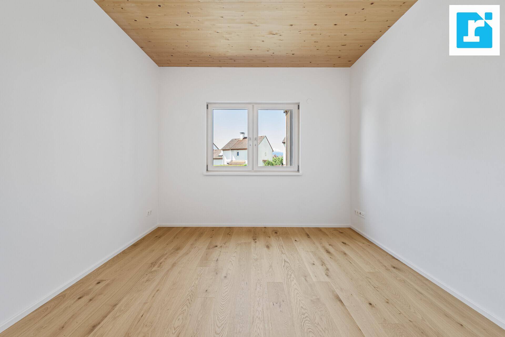 Helles Schlafzimmer mit Parkettboden und Fenster, das einen Blick auf die Umgebung bietet.