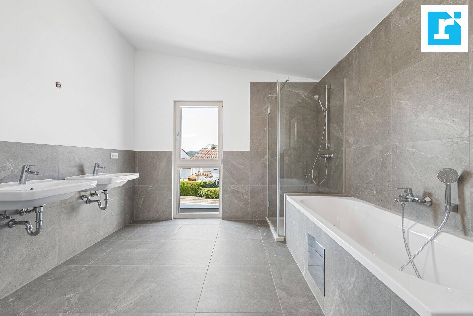 Geräumiges Badezimmer mit zwei Waschbecken, Badewanne und Duschkabine, hell durch großes Fenster.