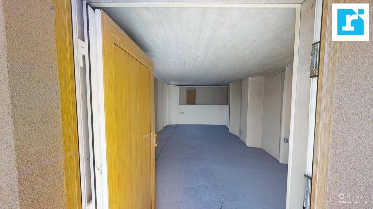 Leerer Raum mit offener Tür, möglicherweise ein Flur, mit einfachen Wänden und Bodenbelag.