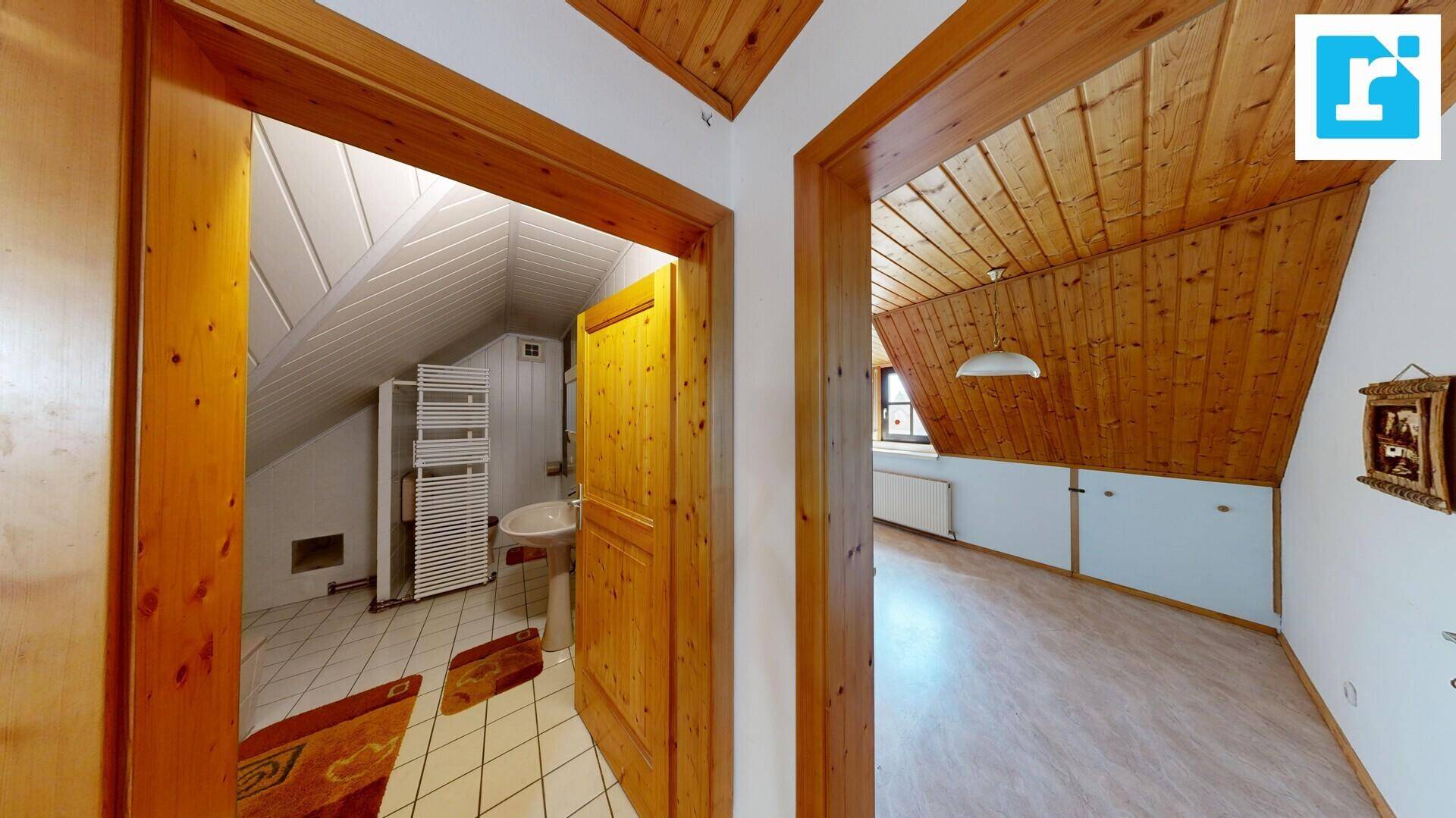 Blick aus dem Dachzimmer in ein Badezimmer mit Waschbecken und Handtuchheizkörper.