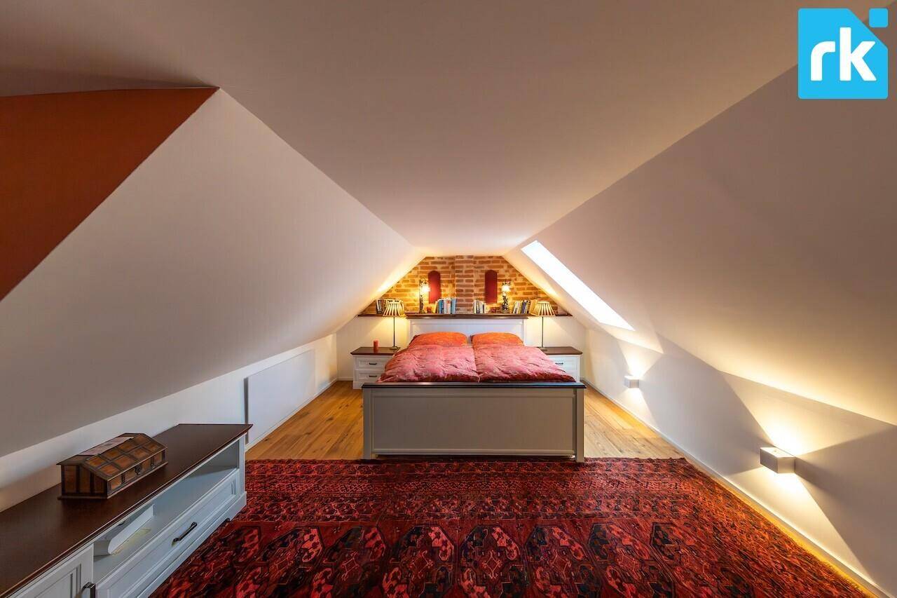 Gemütliches Schlafzimmer im Dachgeschoss mit schrägen Decken, freiliegenden Ziegeln und Dachfenstern.