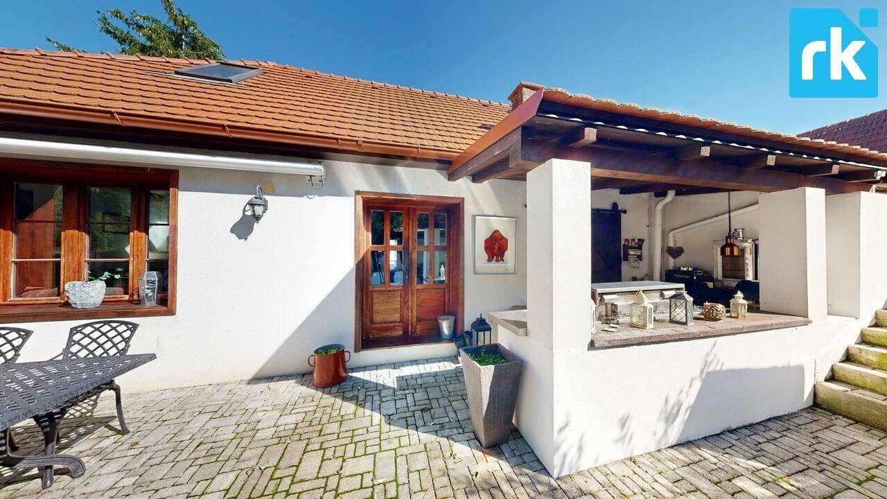 Charmante Hausfassade mit gepflasterter Terrasse und überdachtem Bereich, ideal für entspannte Stunden.