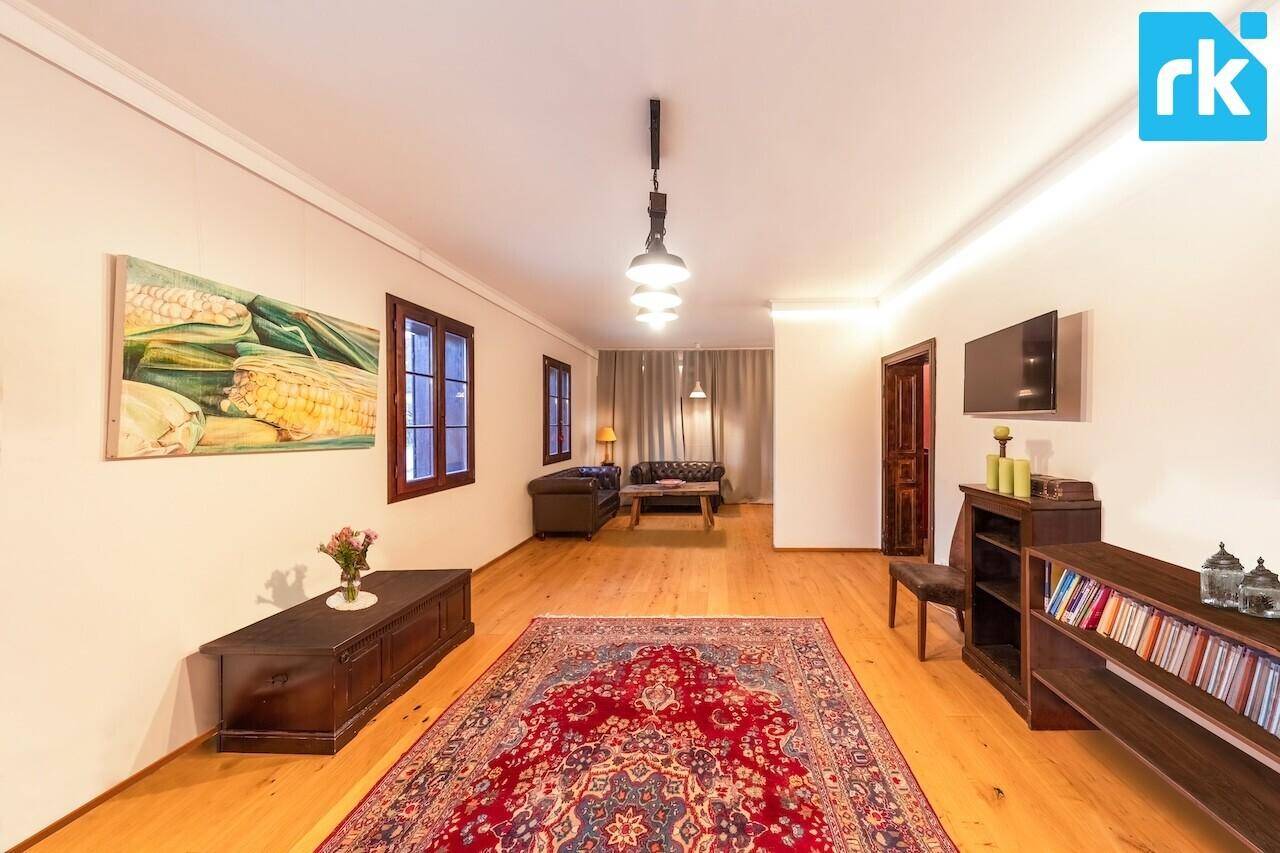 Geräumiges Wohnzimmer mit Holzboden, großem Teppich und traditionellen Möbeln.