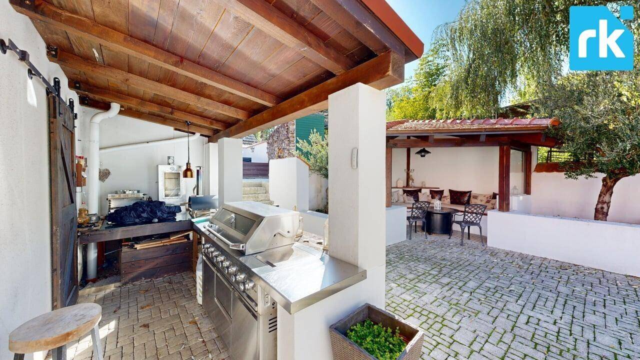 Überdachte Außenküche mit großem Grill und Holzbalken, ideal für Sommerfeste und Kochen im Freien.
