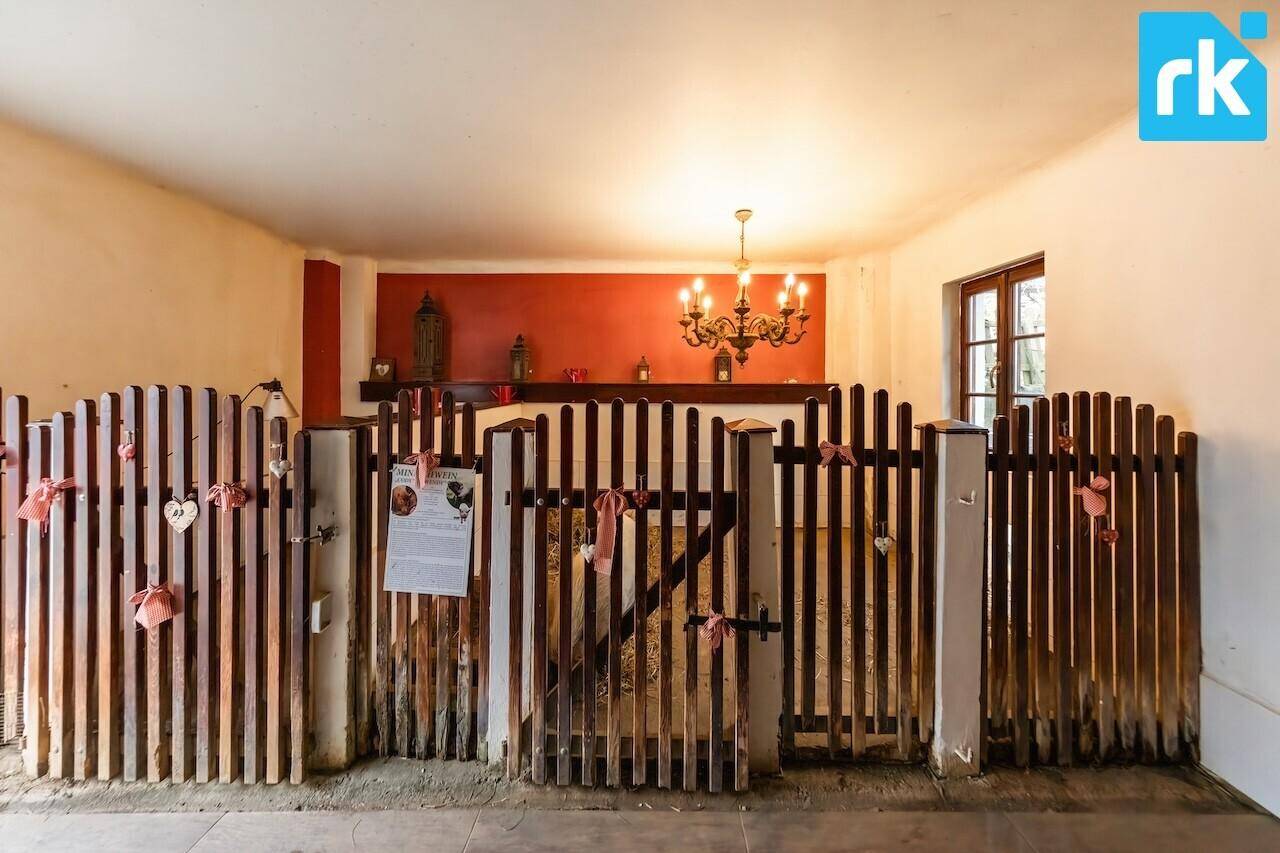 Innenraum mit Holzzäunen und roter Wand, möglicherweise ein Stall oder ein dekorierter Bereich.